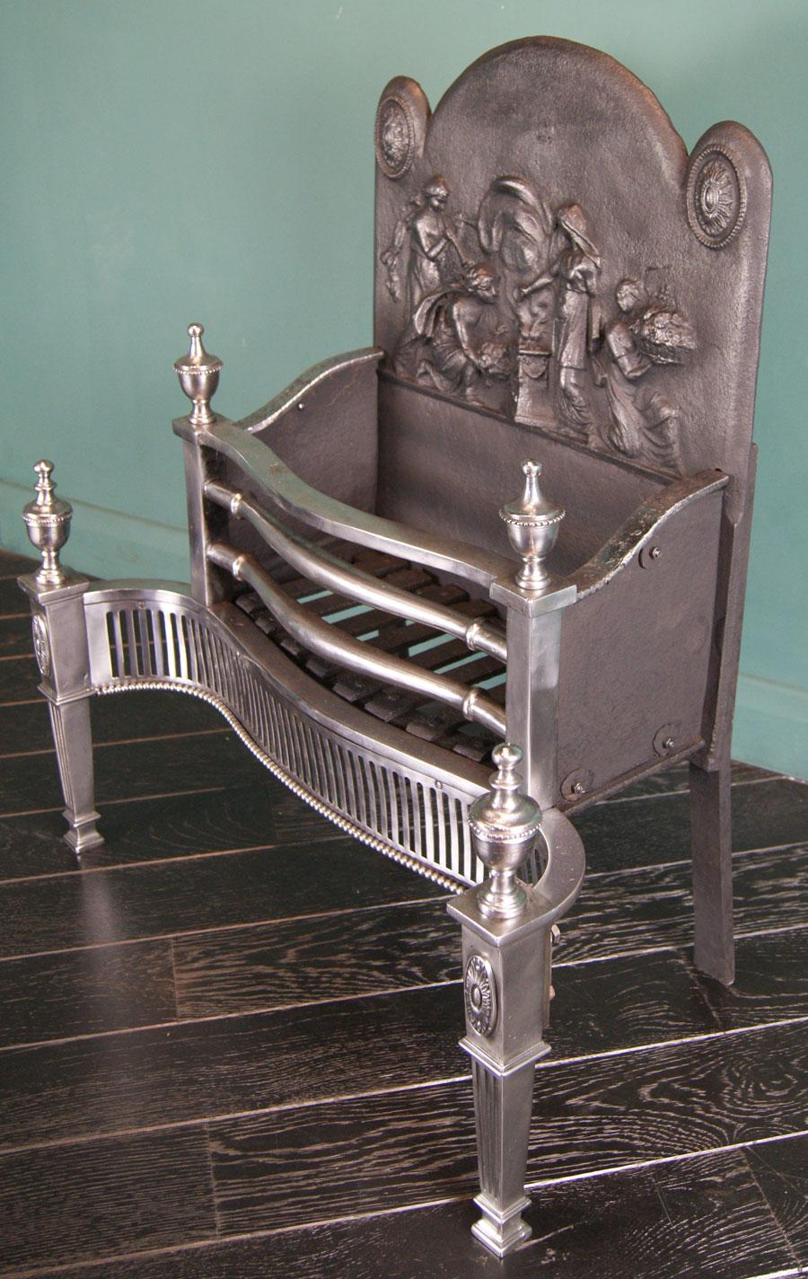 A 19th century polished steel serpentine fire grate, the railed basket with shaped collared fire bars above a fluted fret flanked by square tapering uprights. Fluted fillet details to legs with oval paterae and urn finials uppermost. The rear