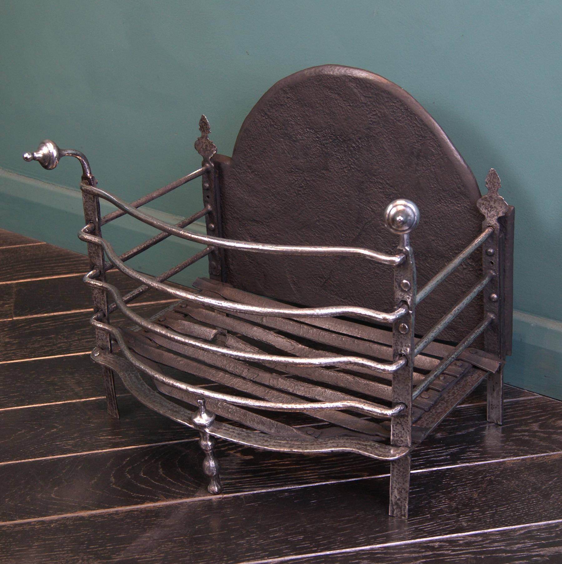 A polished wrought 18th century fire basket in the Dutch form, with finely shaped fire bars, central moulded standard and arched cast iron fireback. Silhouette finials flank the fireback at rear.  Restored.

Circa 1790