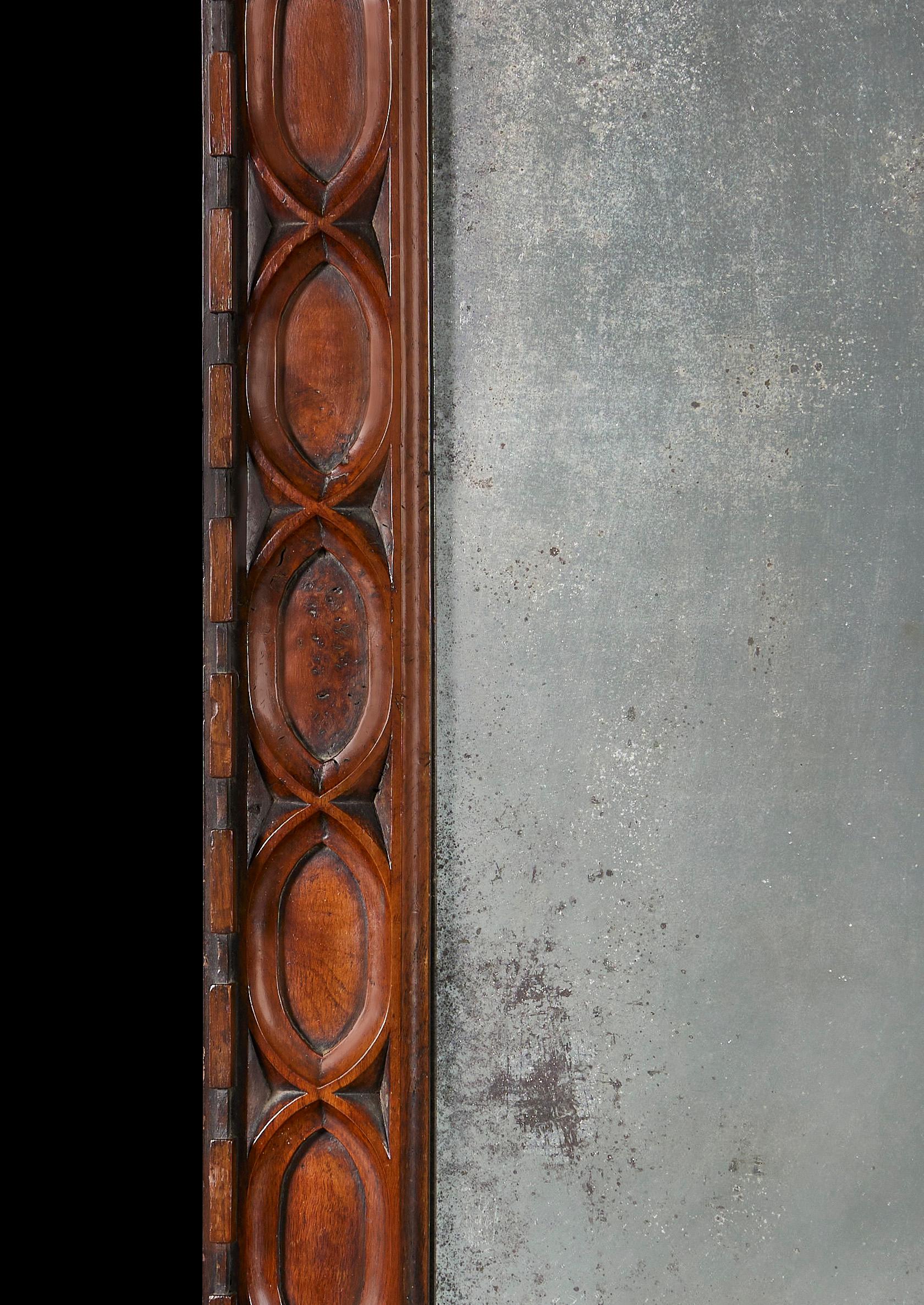 An early nineteenth century pollard oak wooden mirror frame in the Gothic style, with carved interlocking ovals and circles, with stars to each corner. With variated glass mirror plate.