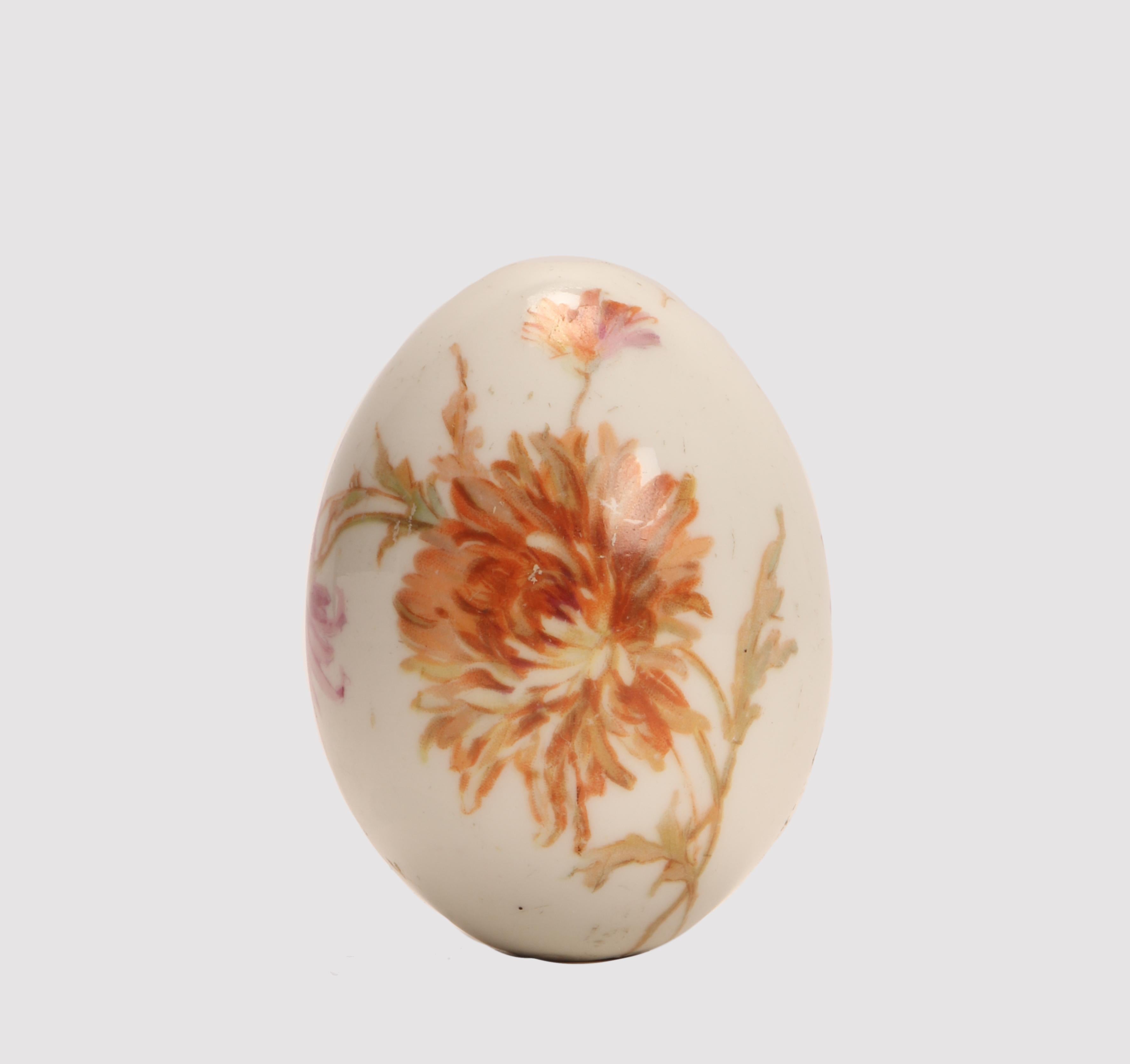 A painted porcelain Easter egg, depicting dahlia flowers on one side, while the cyrillic inscription: Risen Christ on the other side, on a white background. Saint Petersburg, Russia, circa 1890.