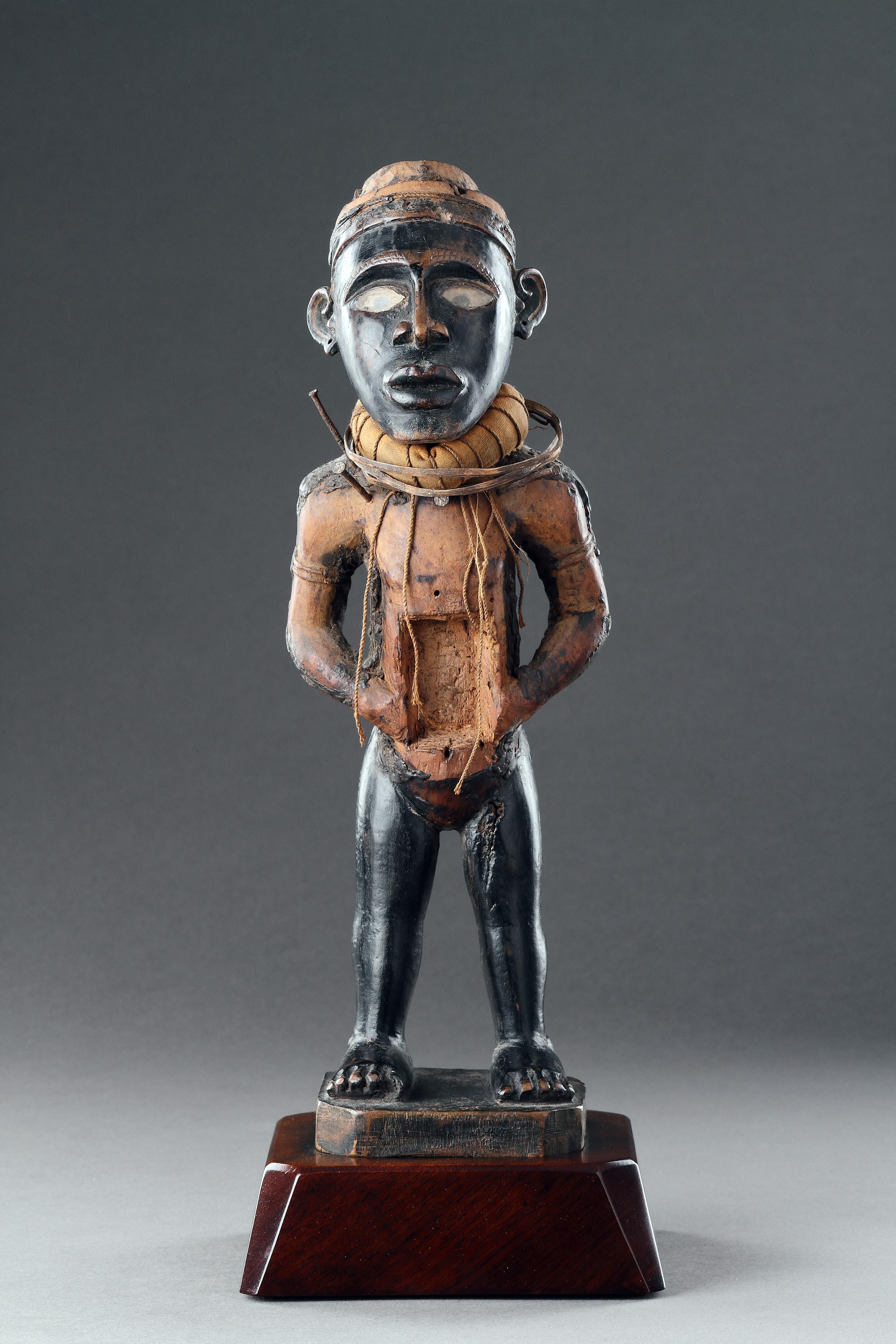 A Powerful Kongo Fetish Figure 
Wood, metal, cloth, nails, glass 
Areas of dark, black lacquered patina, worn through from use
The cavity to the stomach now empty 
Kongo Peoples, Democratic Republic of Congo 
Early 20th Century 

Size: 33cm high -