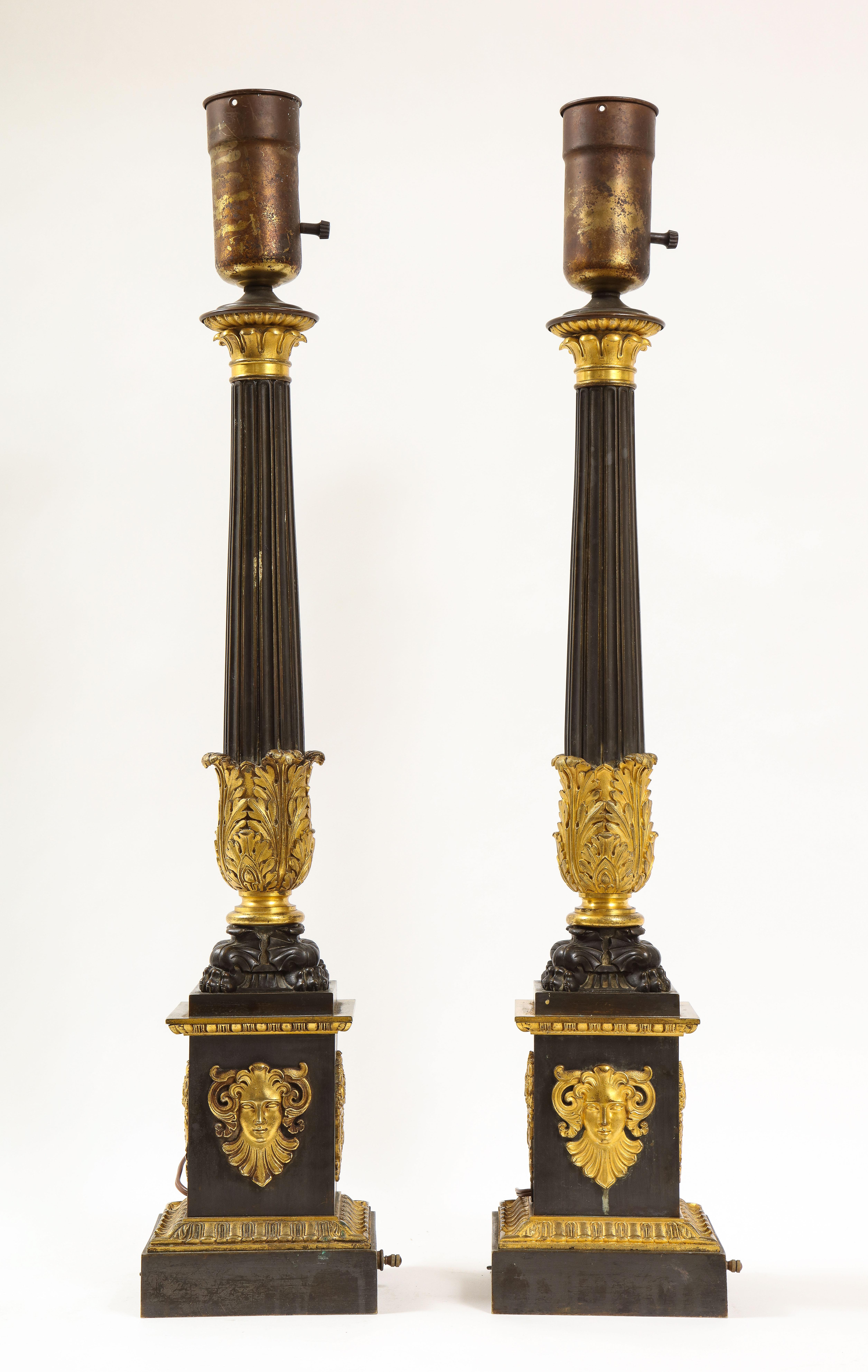 A fantastic pair of French empire period patinated and dore bronze candlesticks mounted as lamps. Each is beautifully cast, hand-chased, and hand-chiseled with the finest quality of burnished and matted dore bronze mounts. The fluted columnar bodies