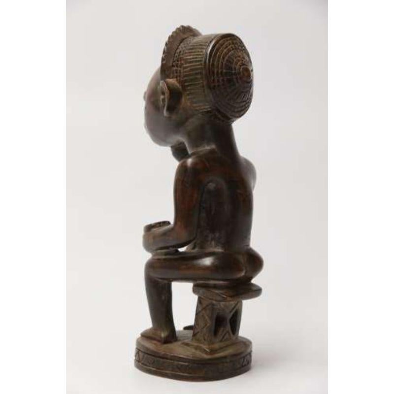 A primitive Angola tribal carved hardwood figure.

This interesting tribal Angola carving depicts a seated tribal female pregnant figure sitting on a naïve stool with a vessel in one hand. This is most likely a fertility figure designed to bring