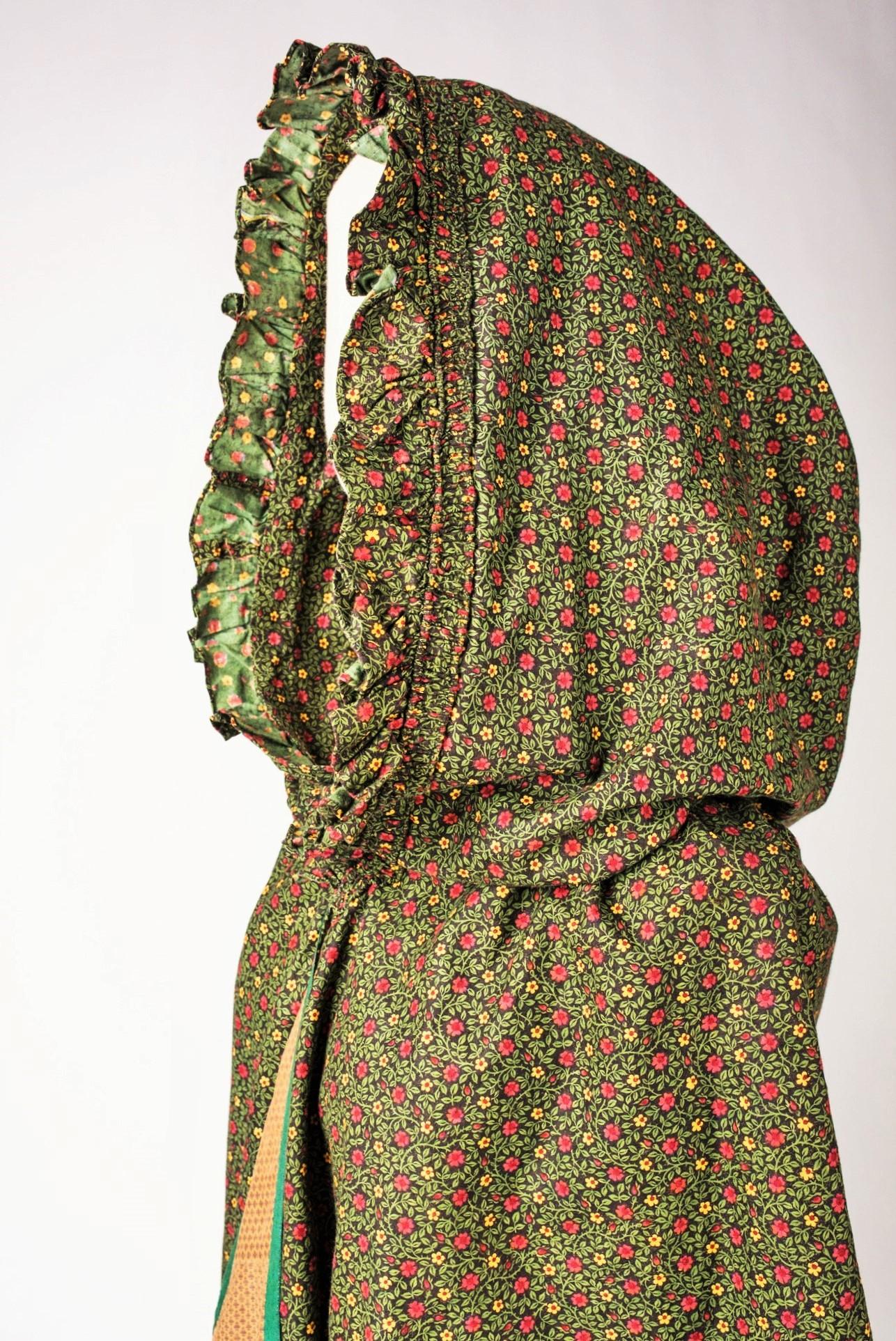 Circa 1800-1810
Provence

A Collecting piece. Beautiful chintz cotton Visit/Cloak with Mille Fleurs decoration on a brown background, including a large hood with gathered falbalas, inspired by the mounted headdresses of the french Louis XVI period.