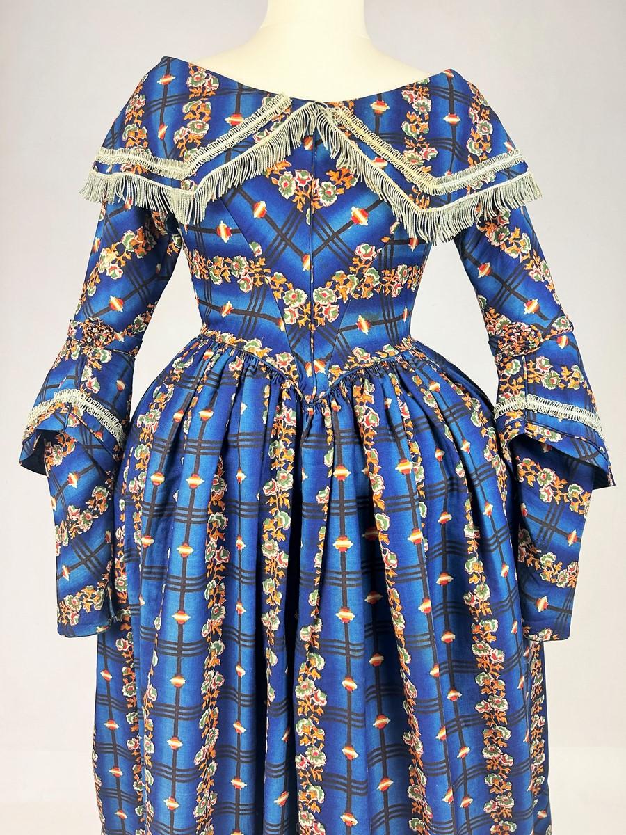 Circa 1840-1845
England

Beautiful British bourgeoisie day dress, in blue wool Challis shaded with stripes and printed with a stream of roses. It dates from the early Victorian era in England. The bust is curved and pointed, with a wide Berthe