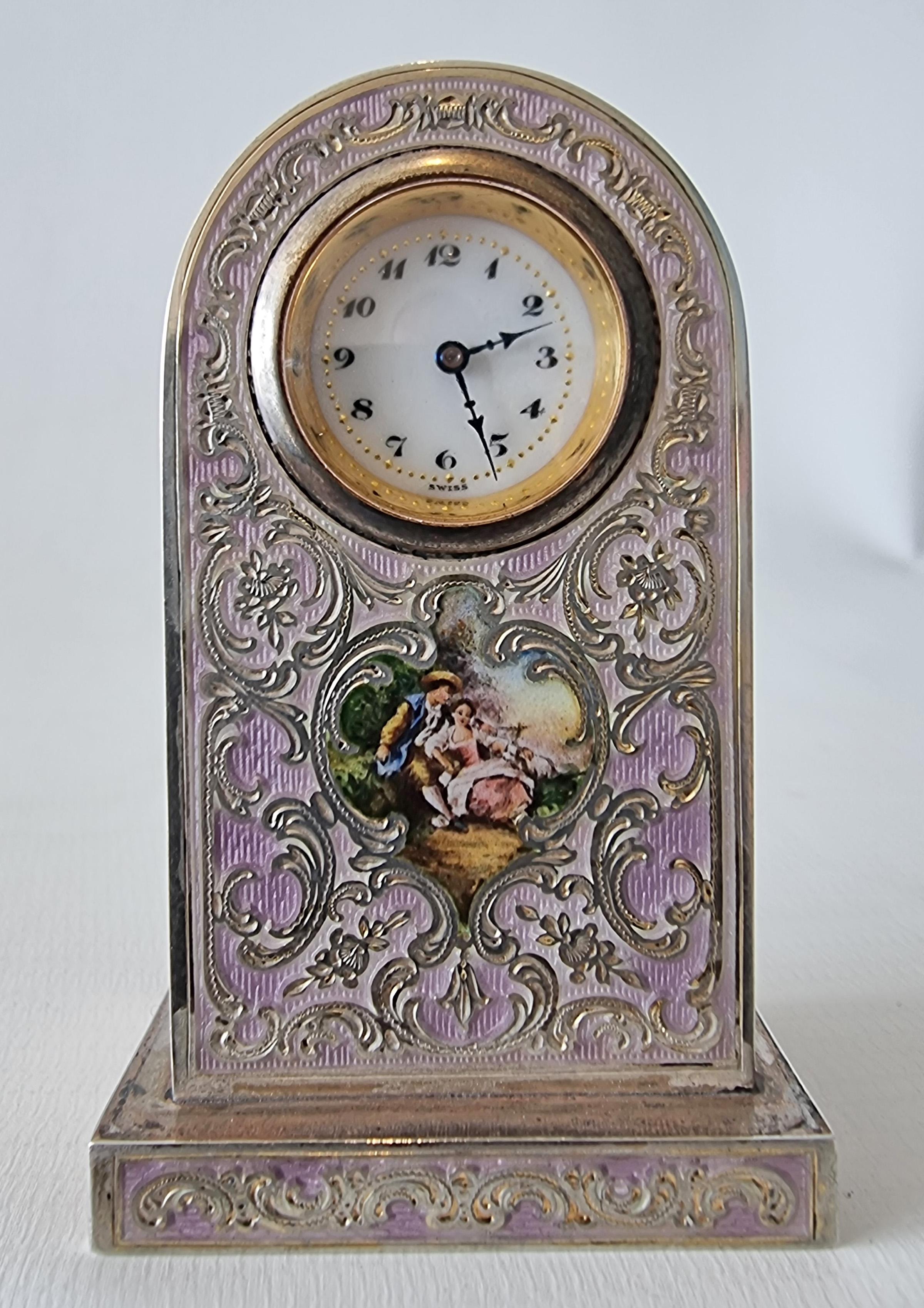 An unusual gilt metal  and purple guilloche enamel boudoir clock with superb inlaid designs of flowers and swags and a hand painted picture to the front of a couple.  With enamel dial with arabic numerals and blued steel hands. Marked underneath 6 o
