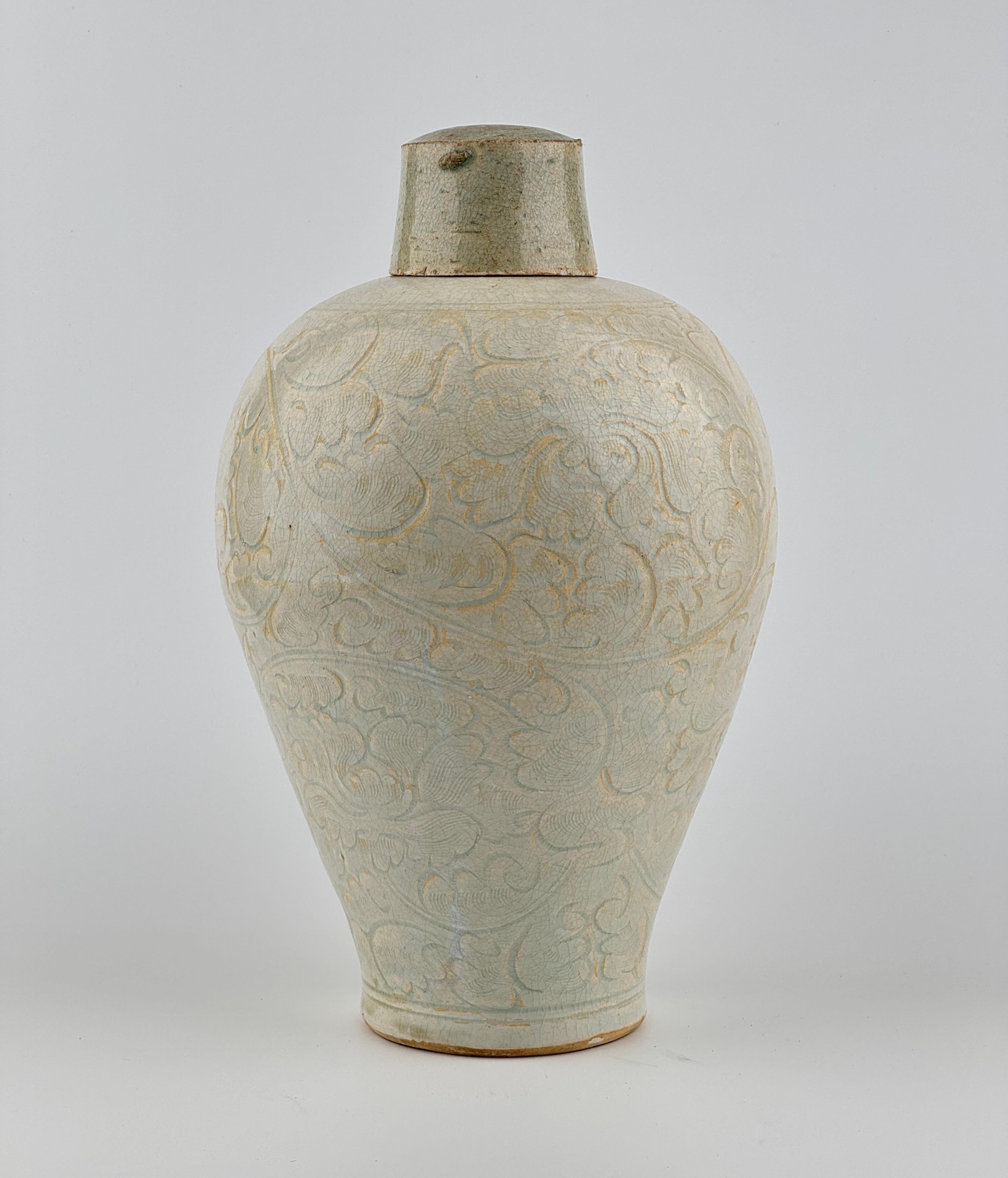 Il vaso presenta una struttura finemente lavorata, caratterizzata da spalle larghe e lati allungati e affusolati, sormontati da un collo cilindrico compatto e scanalato. L'esterno è ornato da intricati motivi di fogliame a scorrimento, accentuati da