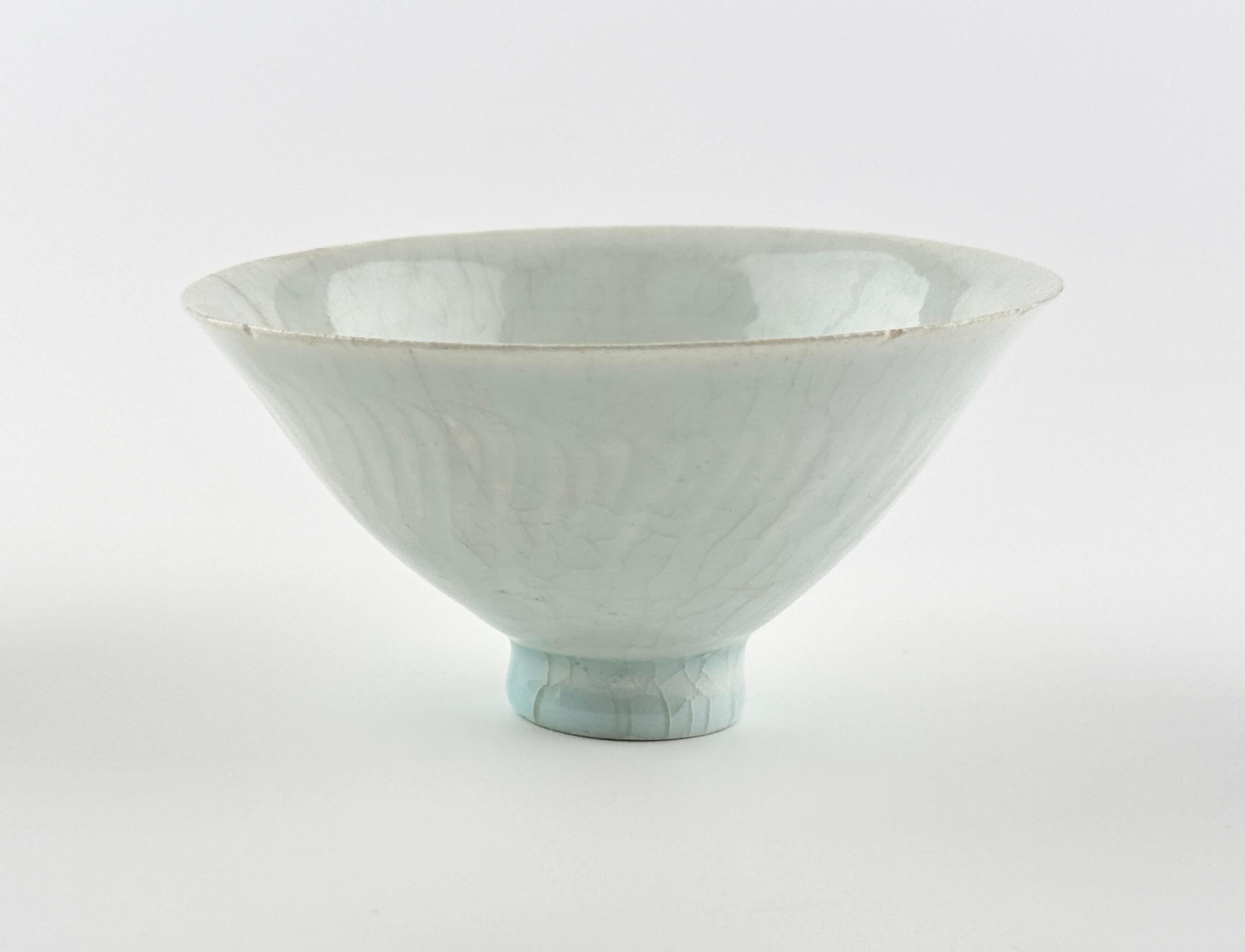 Ce bol de Whiting est fait d'argile blanche fine, recouverte d'une glaçure translucide teintée d'une nuance bleuâtre pâle. L'extérieur est subtilement décoré de motifs de pétales de lotus (lianban) en bas-relief, sans saillies prononcées. La surface