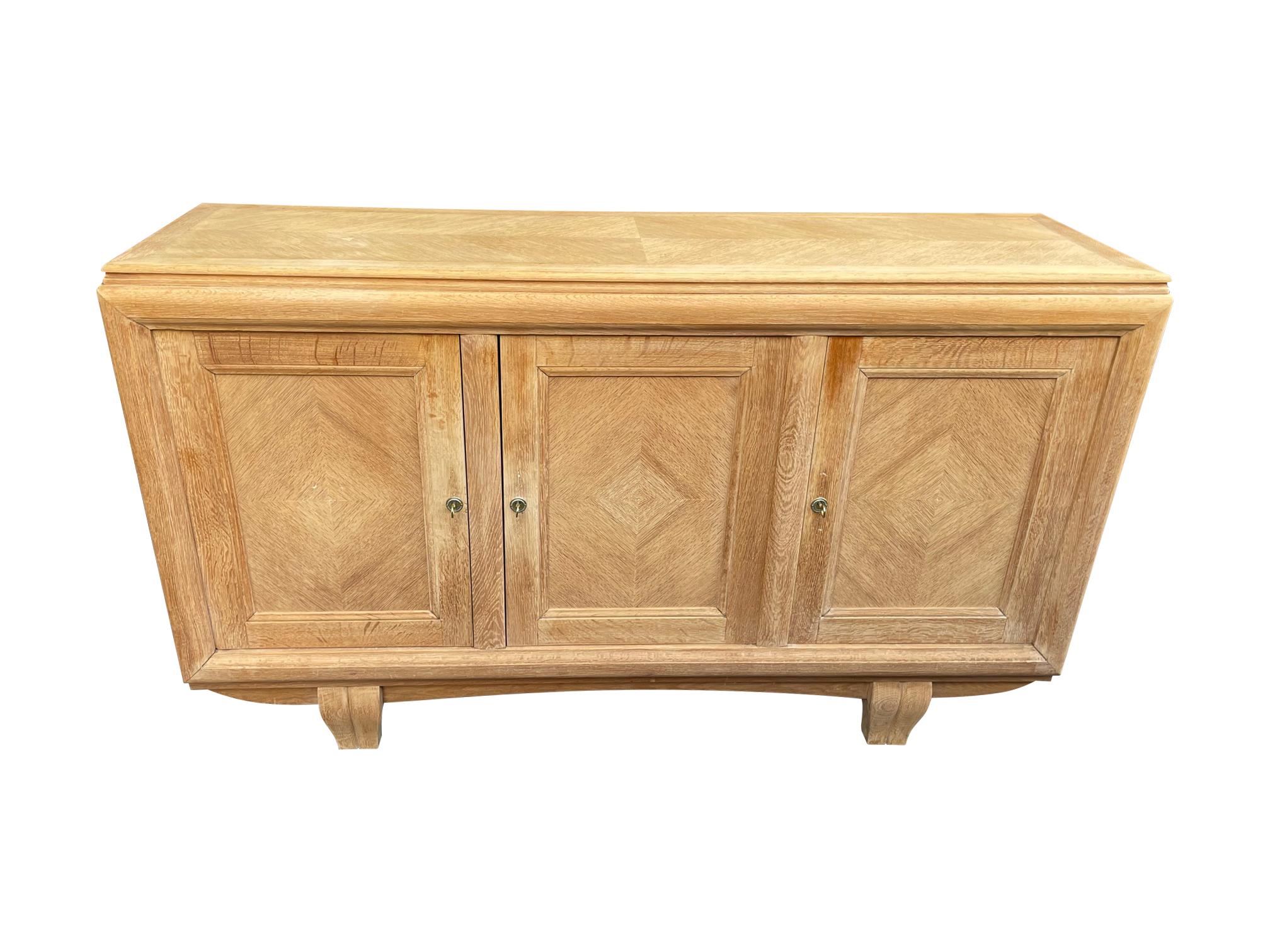 A quality 1940s natural oak three door sideboard by Gaston Poisson with wonderful diamond pattern detail doors, solid curved oak front feet and solid oak top with chevron inlay detail. With three orignal brass and nickel keys with orignal circular