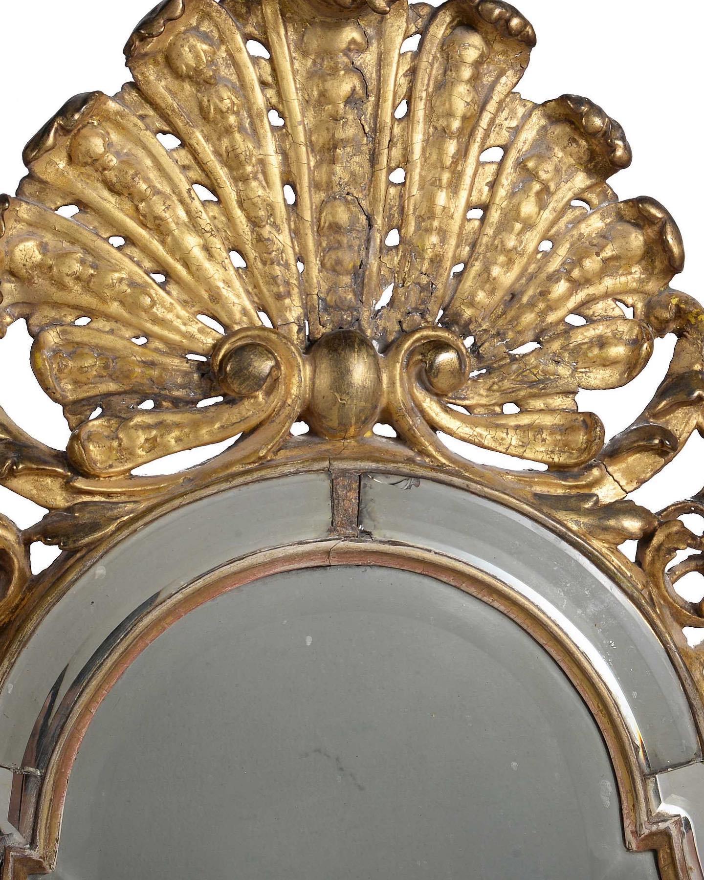 A rare Queen Anne carved giltwood and gesso wall mirror, c.1710. Surmounted by a large Baroque shell, above a bevelled arched central plate and framed by marginal plates.

Measures - 105 cm H x 57 cm W.

