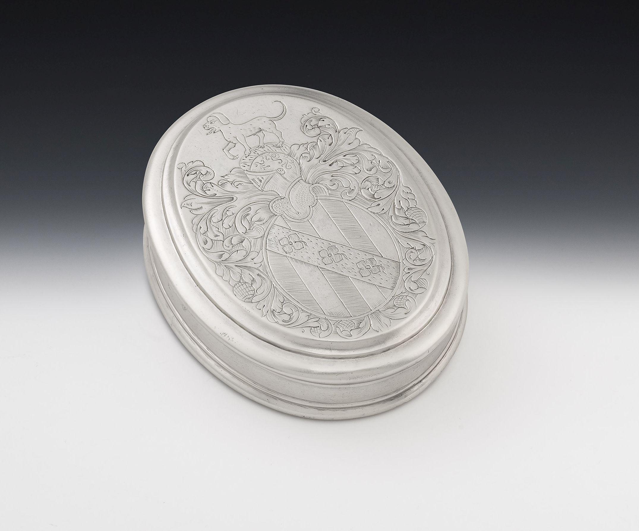 An important Queen Anne Britannia Standard Armorial Tobacco Box made in London in 1709 by Edward Cornock.
This Box is of typical oval form with a reeded edge on the base. This example has a pull-off cover displaying some of the finest engraving
