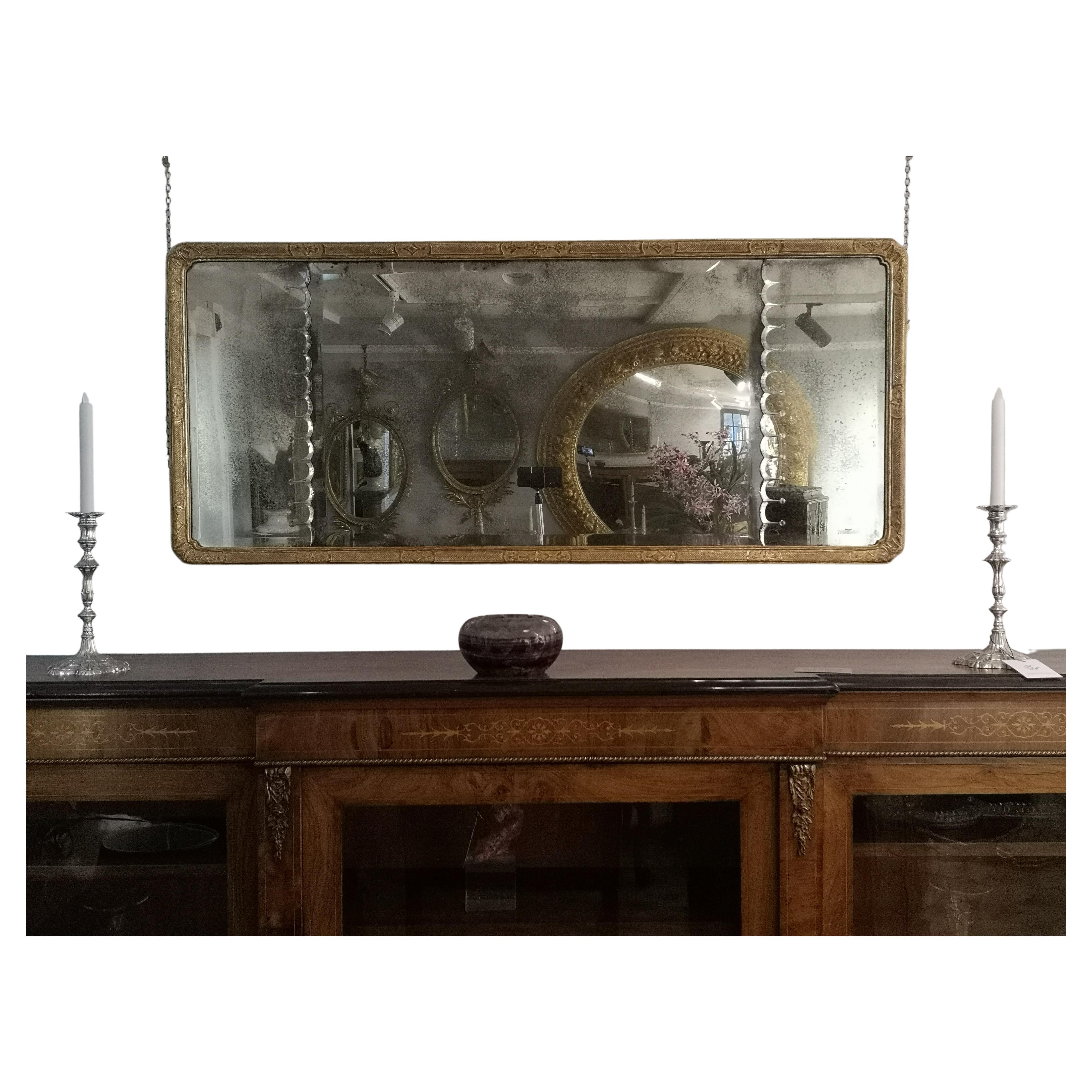 A fine triple mercury plate gilded wood and gesso overmantel mirror, the divided silvered and bevelled glass with scalloped edging to the outer sections, the rectangular frame having a running link inner with the mainframe decorated with