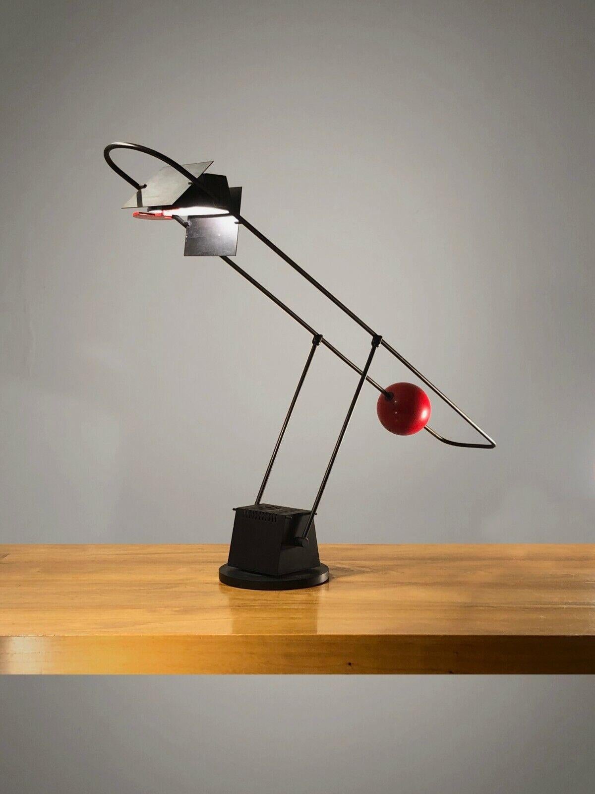 
781 / 5 000
Résultats de traduction
Résultat de traduction
An exceptional large counterweight desk lamp, Post-Modernist, Constructivist, Memphis, weighted pyramidal base in black lacquered metal housing the transformer, double-adjustable arm using