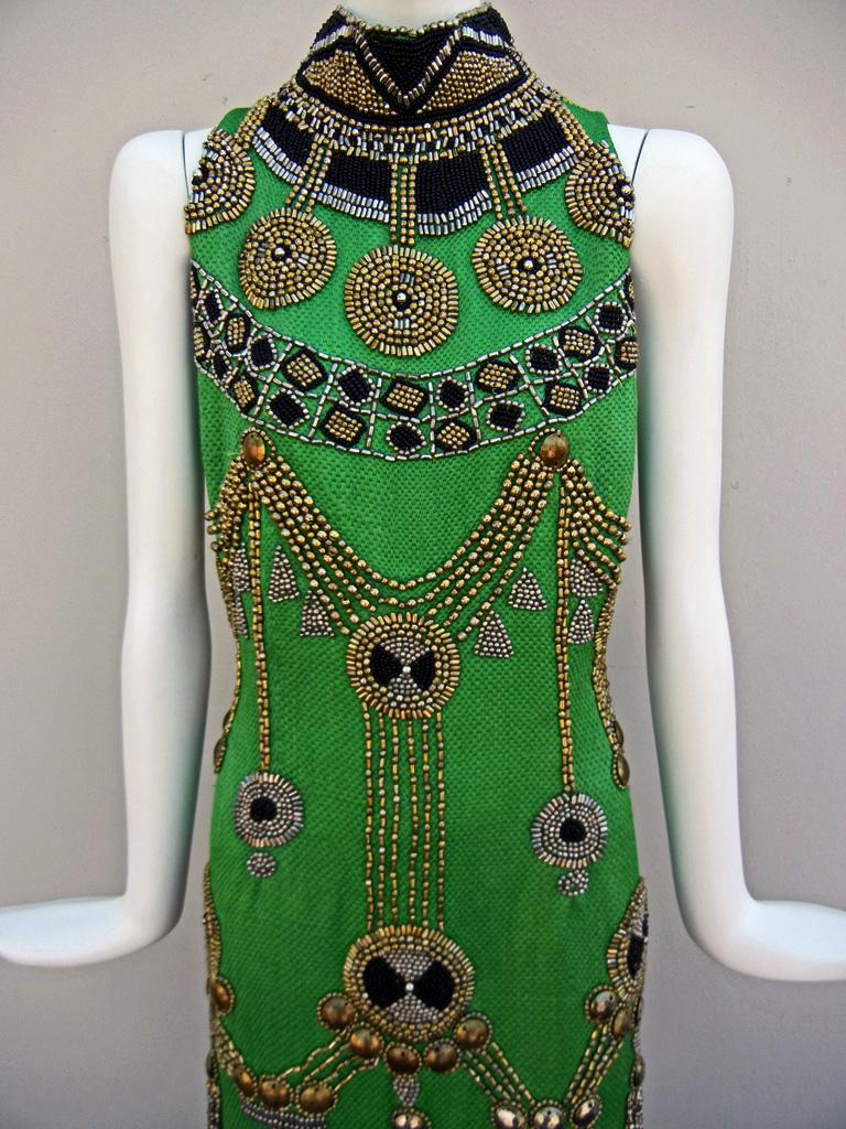 Rare 1990 custom made gown designed by Gianni Versace for his Versace Atelier label.   High neck sleeveless dress fashioned of rich green damask silk; adorned throughout with weighty hand beaded brass and gold tone beads with an Egyptian flair.   