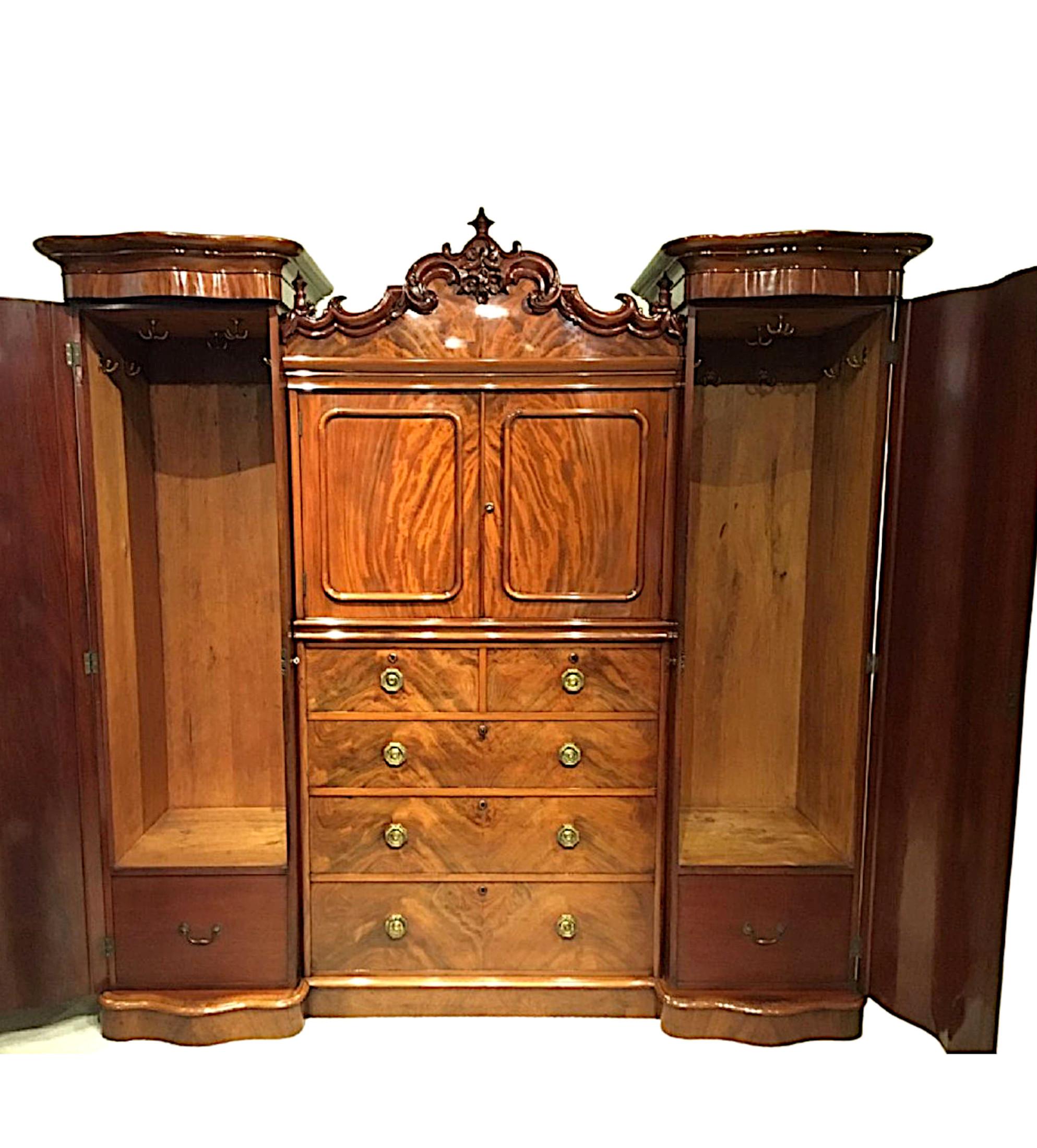 A very rare 19th Century flame mahogany wardrobe The central section with a beautifully ornate arched top adorned with finely carved foliate, finial and c - scroll decorative motifs, raised above two moulded panelled doors, opening to reveal shelved