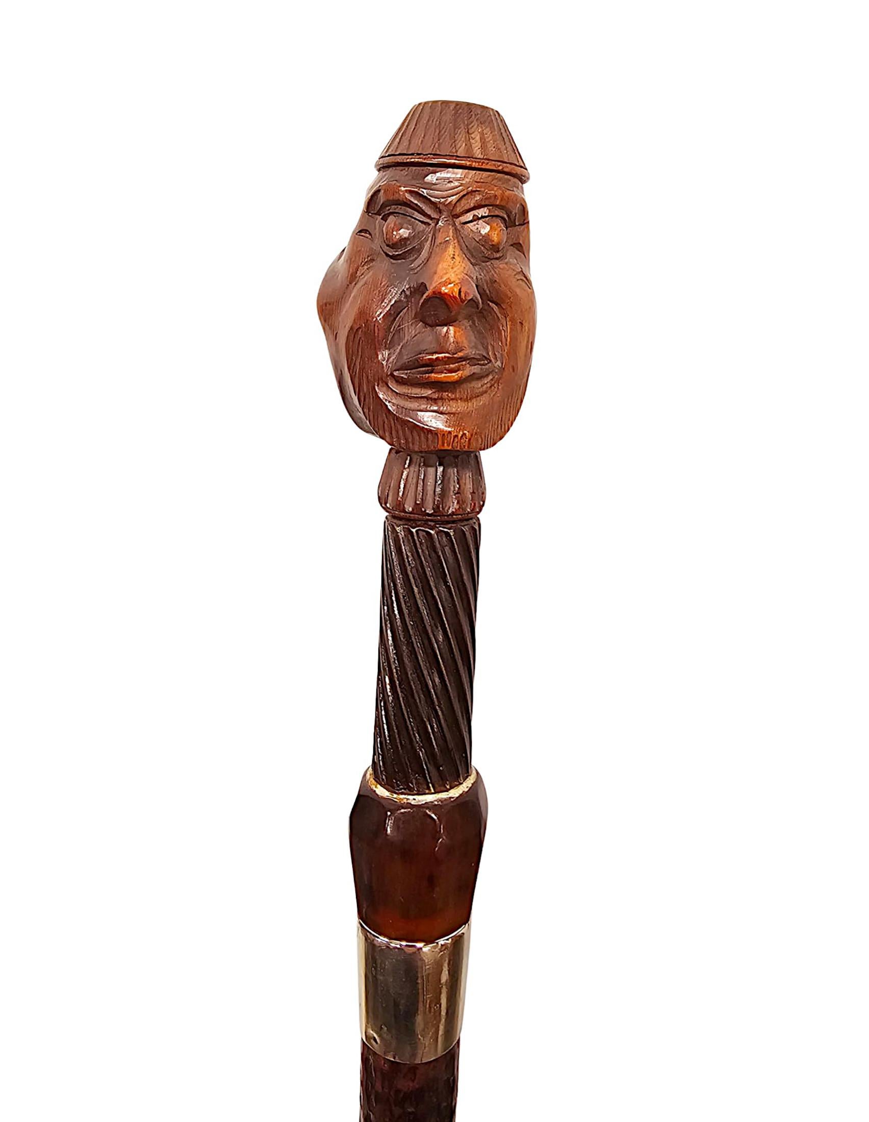Une canne très rare du 19ème siècle, bien figurée, avec un casse-noix en forme de gadget.  Cette pièce exceptionnelle est superbement sculptée à la main, avec une patine riche, un grain, un collier monté en argent et est surmontée d'une paire de