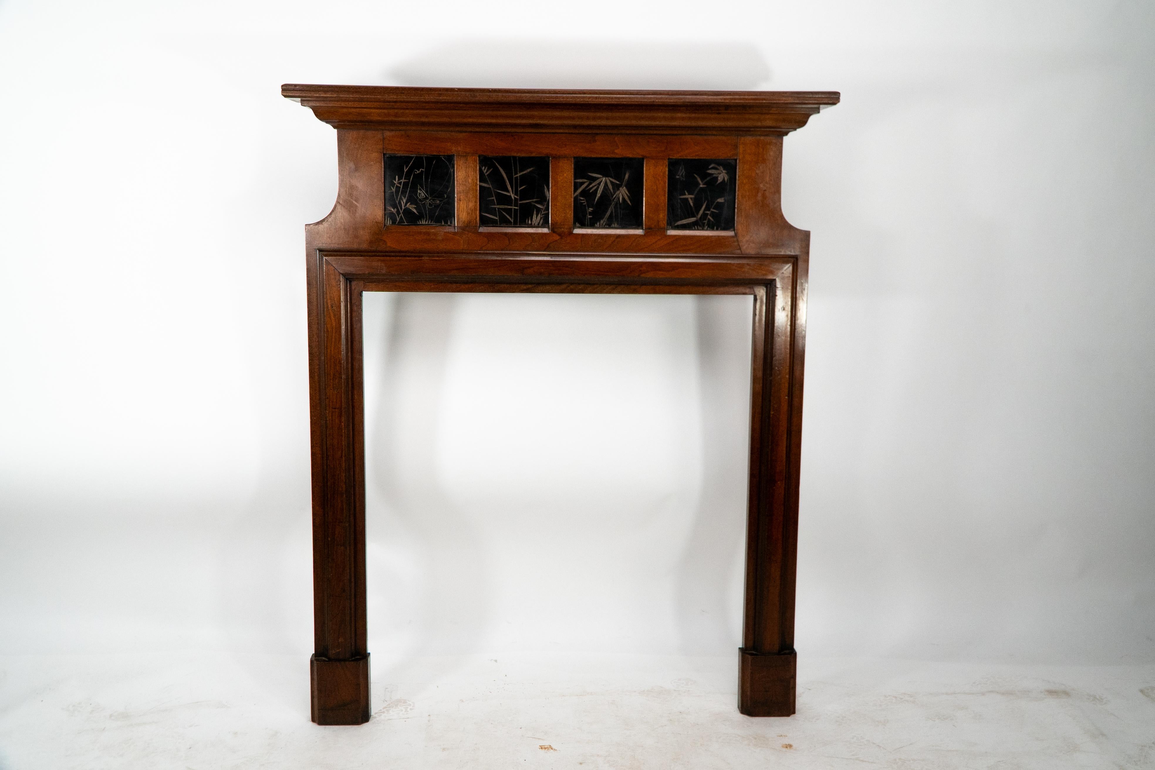 Thomas Jeckyll for Barnard Bishop and Barnard. A rare Aesthetic Movement Walnut fire surround, the mantel with molded edges and four ebonized panels incised with butterfly and bamboo stems and leaf decoration in the Japanese style with further
