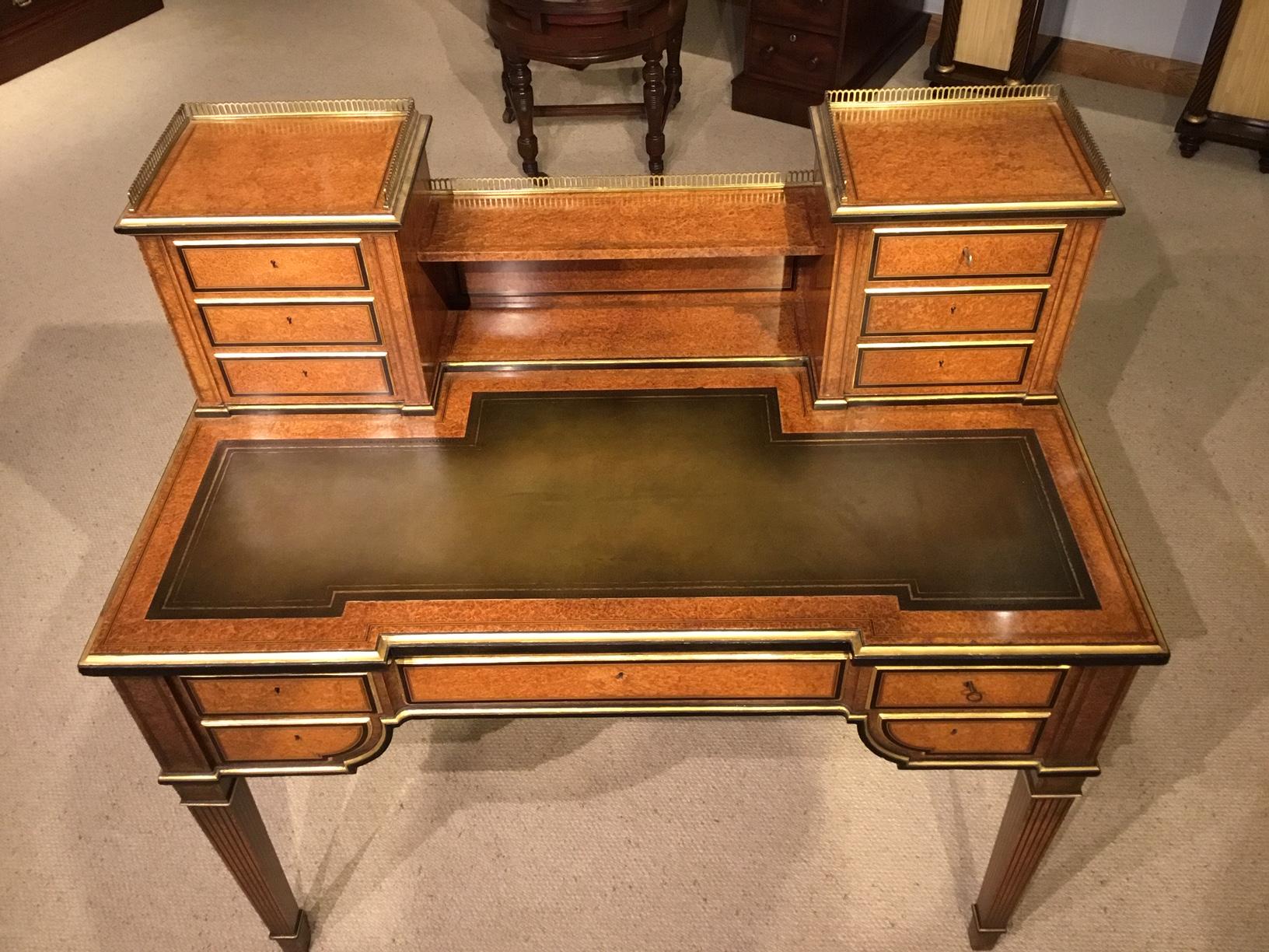A rare amboyna, parcel-gilt and ebony Victorian period antique writing desk. Having a raised super structure with a brass gallery with six rectangular mahogany lined drawers and a shelf, veneered in the finest amboyna with parcel gilt detail and
