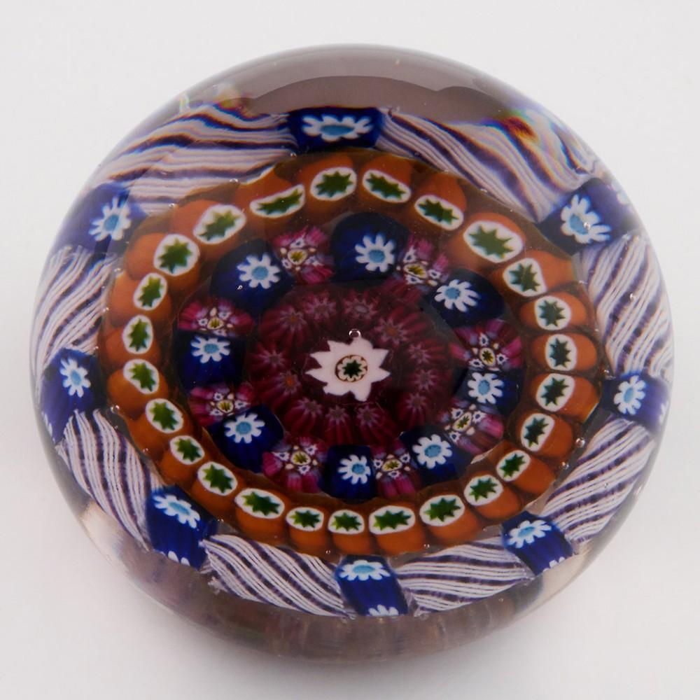 A Rare And Early Paul Ysart Concentric Paperweight on Clear Ground, c1940

Additional information:
Date : c1940
Origin : Scotland
Features : Three concentric rings of polychrome complex canes around central cane with outer ring of canes and