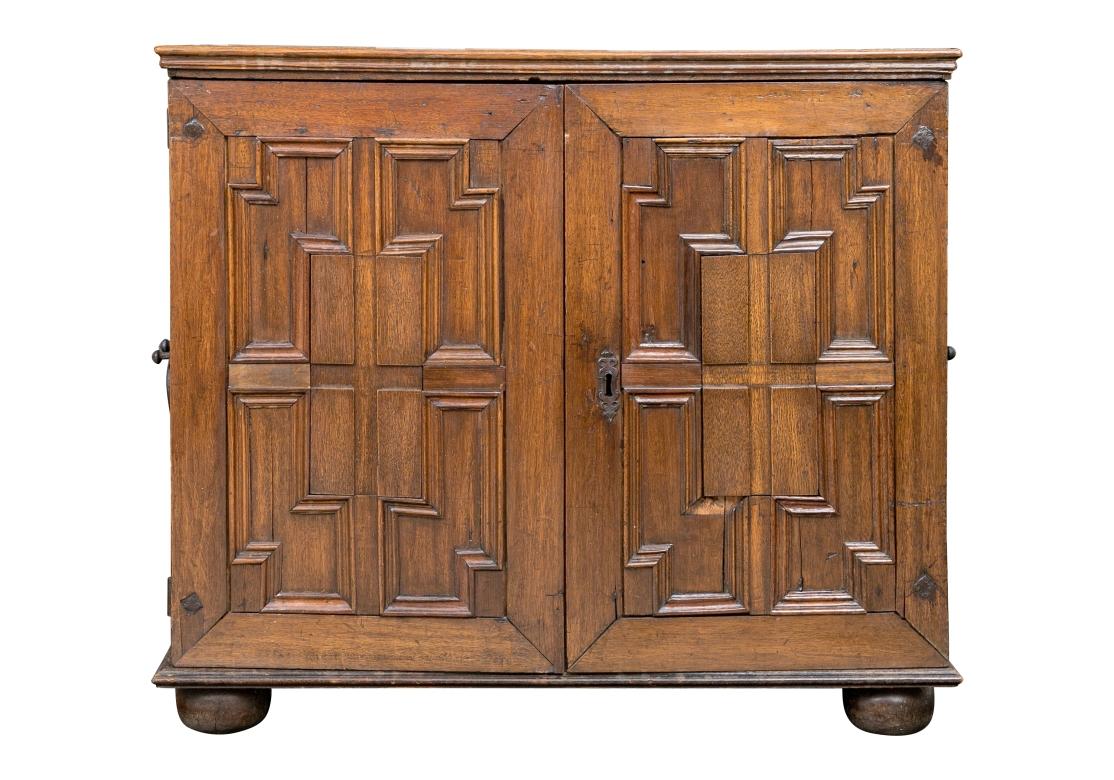 A very early Oak Spice Chest with fine English form, handsome decorative panel doors and 24 drawers, four of which are hidden behind a central interior door. The Spice Chest features exceptional original interior strap hinges as well as bold Oval