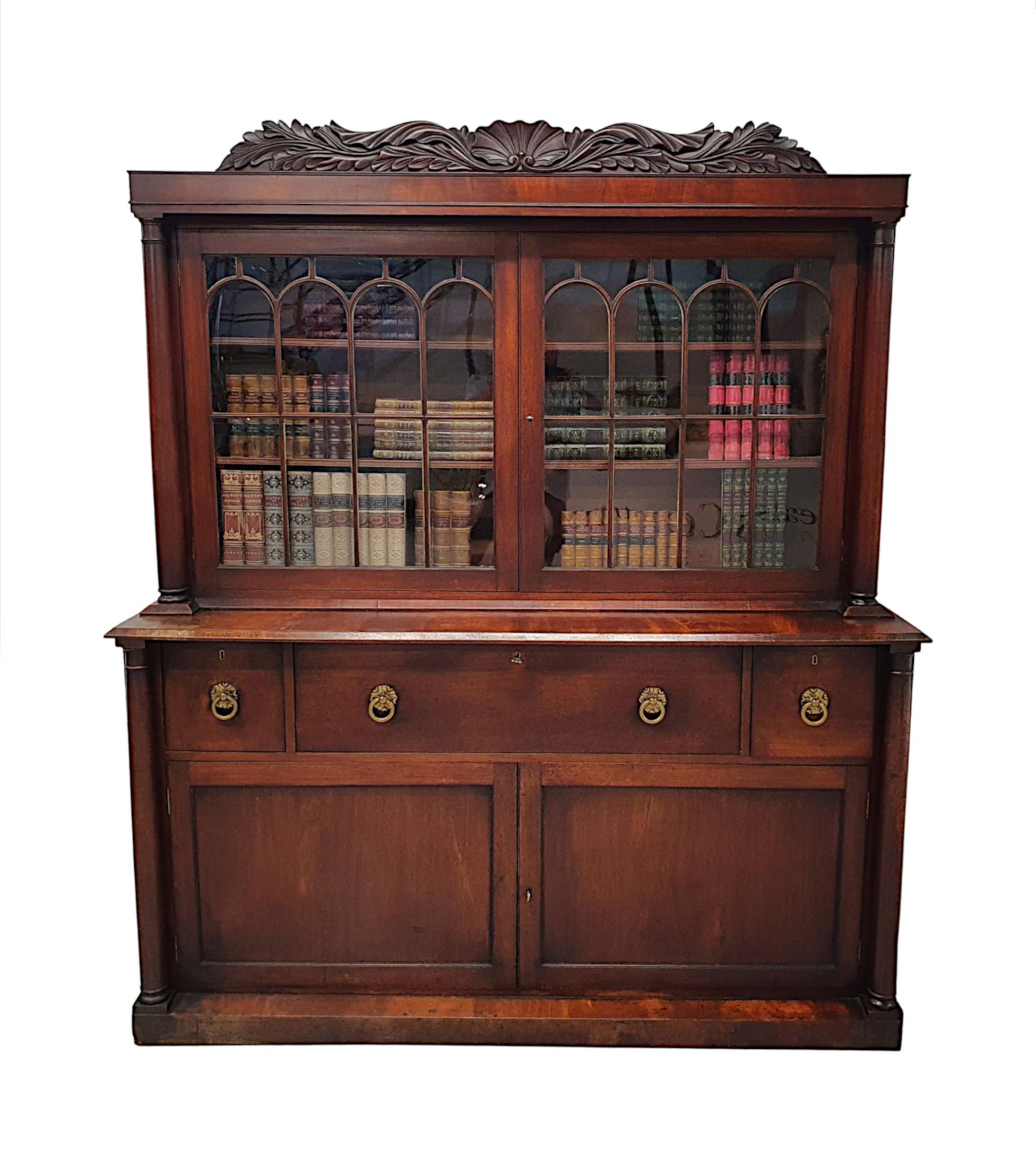 A rare and fine early 19th Century William IV Irish flame mahogany secretaire bookcase, beautifully hand carved with a rich patina.  The pediment with a stunning centred scallop shell flanked with scrolling foliate motif detail carved in high