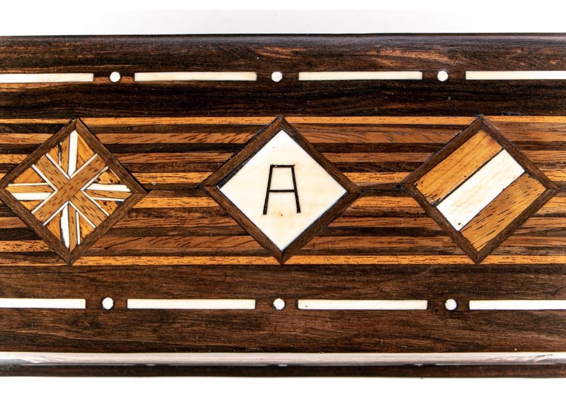 An exotic rectangular wood box with parquetry striped, square and diamond inlays and monogrammed center lid diamond with an “A.” Bone details. Double compartments inside. Leather bottom. The box has a very soft hand from a well crafted finishing of