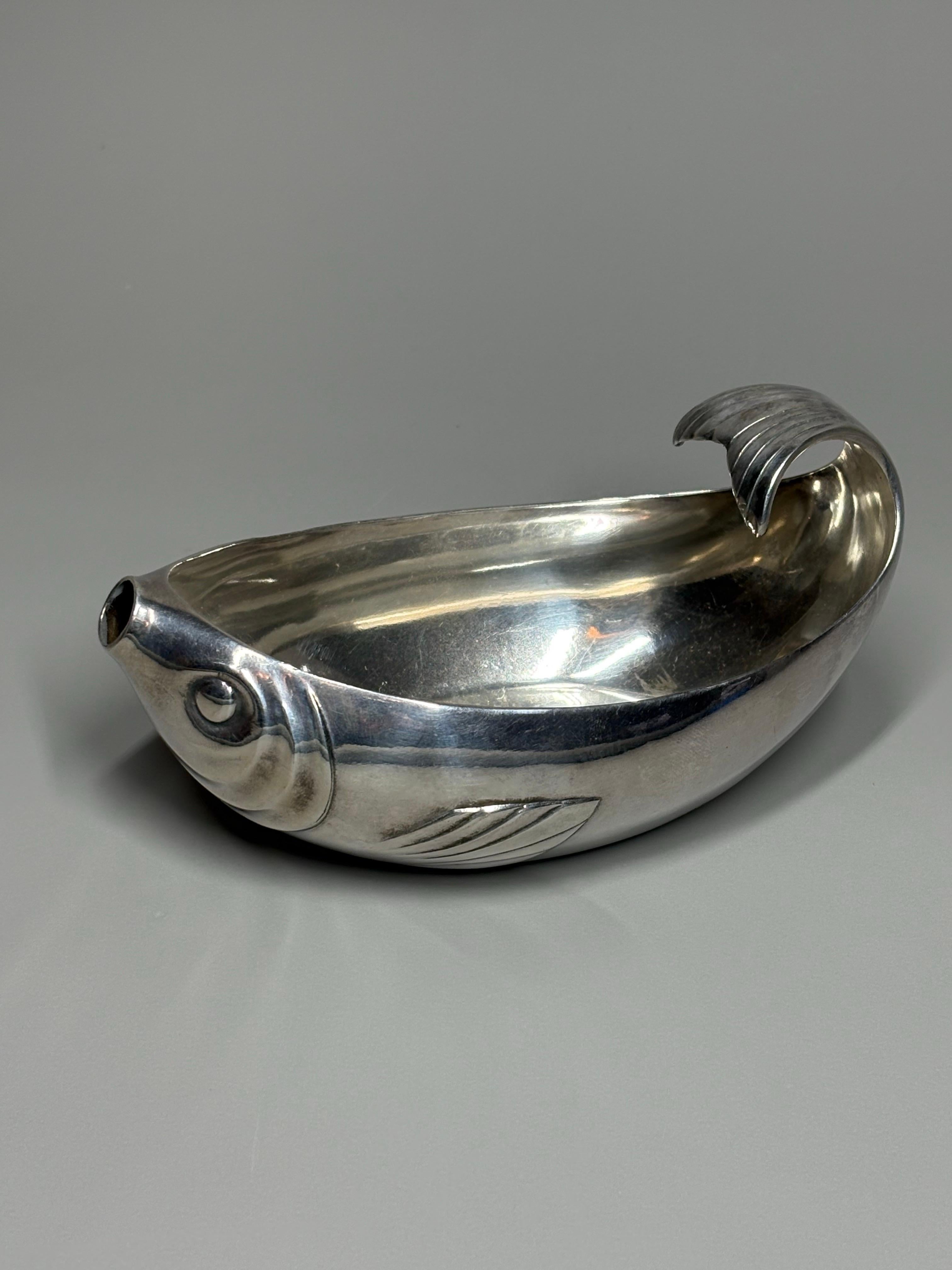 Rare saucière en laiton argenté Art Déco de Gallia pour Christofle en forme de poisson stylisé, la queue courbée du poisson formant l'anse et sa bouche formant le bec verseur . Poinçon 