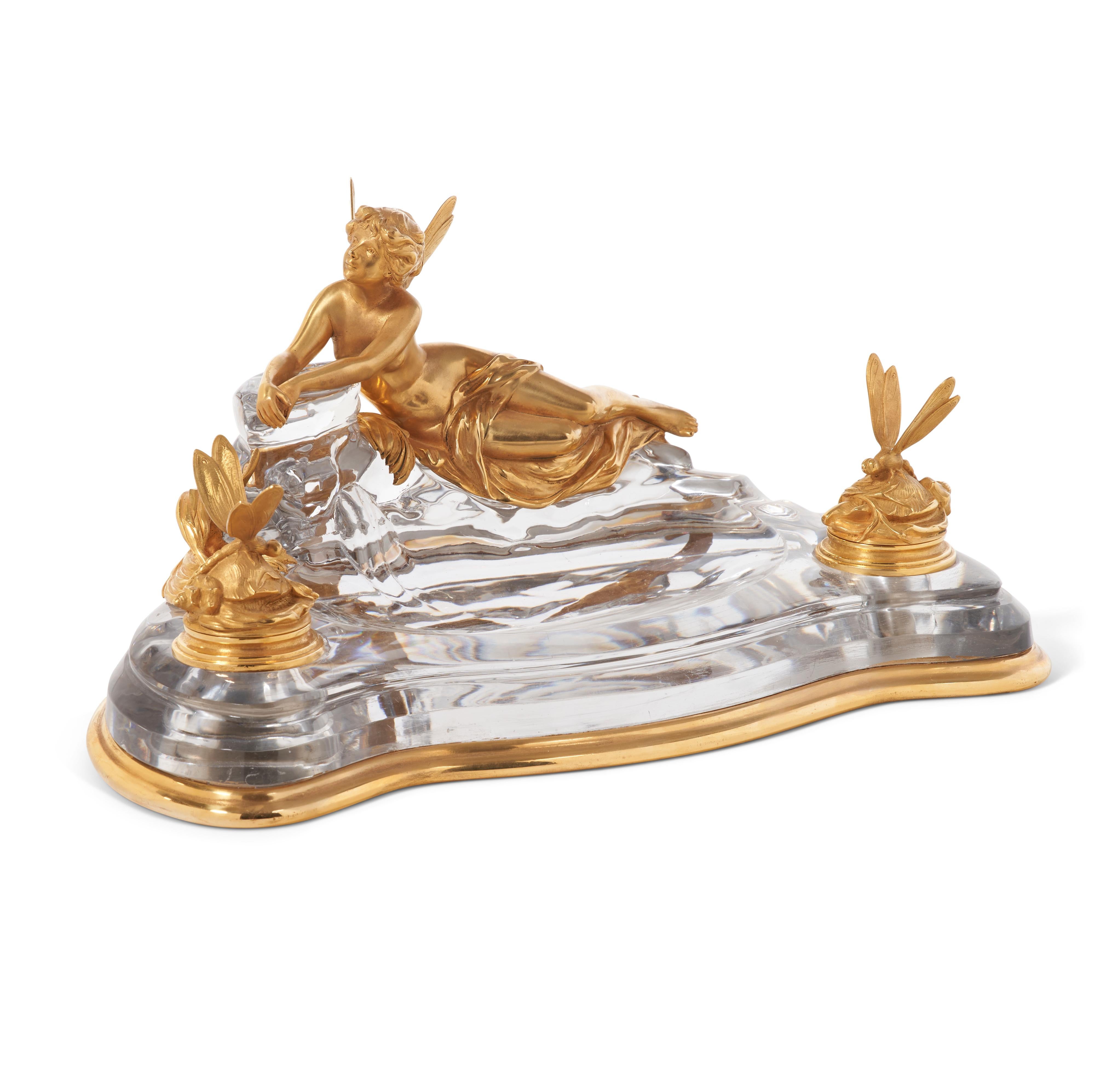 A Rare Art Nouveau French Ormolu and crystal inkwell Encrier by Baccarat, circa 1900, the ormolu possibly by Francois Linke.

Depicting a reclined winged maiden resting on a crystal rock, ,the two inkwells each with a hinged lid formed as a