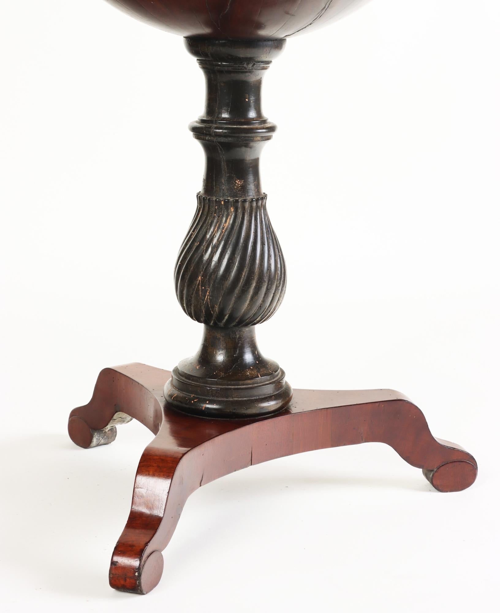 A rare Biedermeier mahogany globe table or official known as Globustisch on tripod base with ebonized stem. 
 The retractable globe-form top with segmented veneer panels open to reveal an interior fitted to reveal with secret compartments and