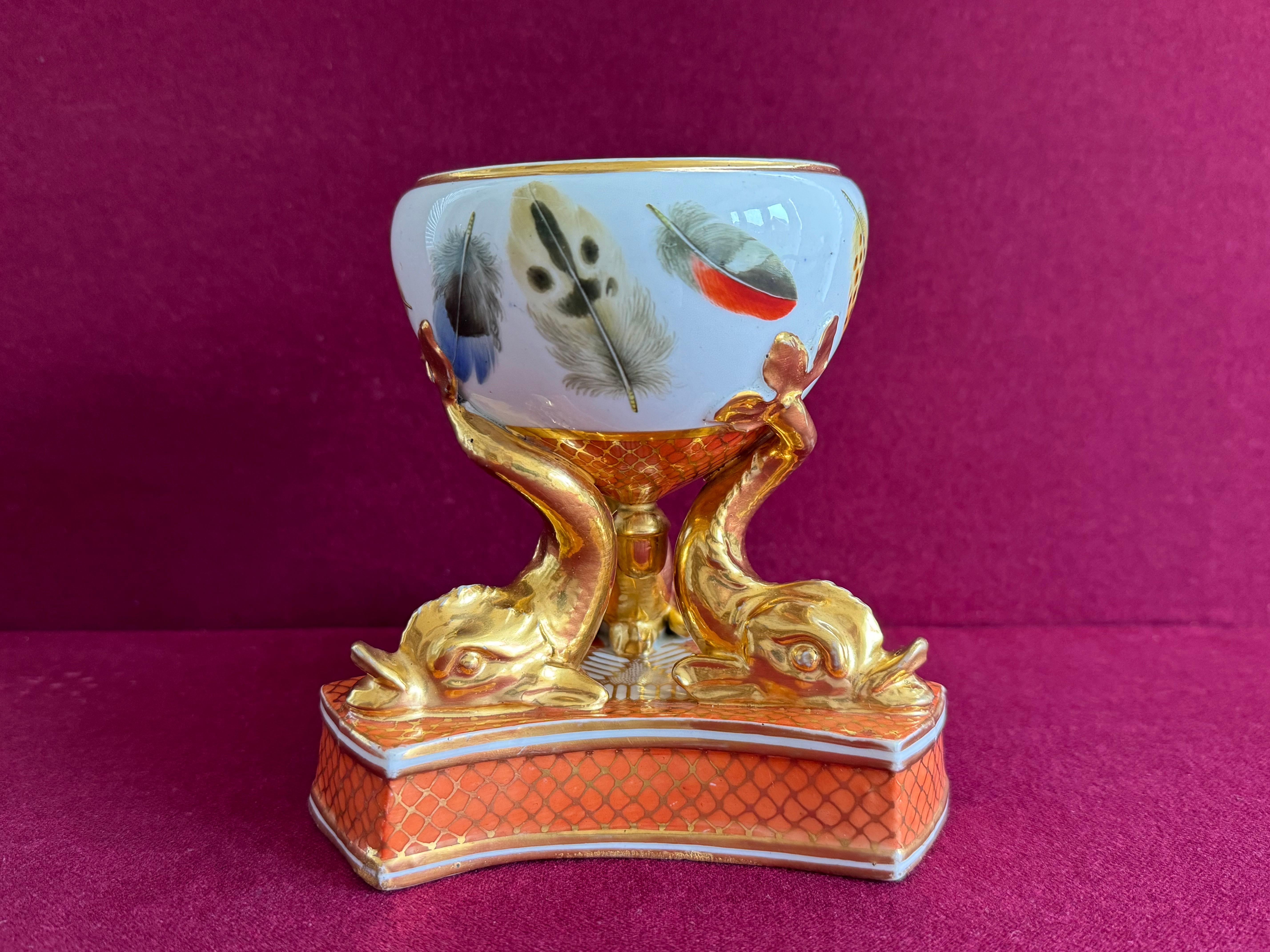 Raro quemador de pastillas de porcelana Chamberlains Worcester c.1807 - 1811. El cuenco globular está sostenido por tres delfines dorados sobre una base triangular, ricamente decorada con un fondo naranja vibrante y una red dorada. El cuenco está