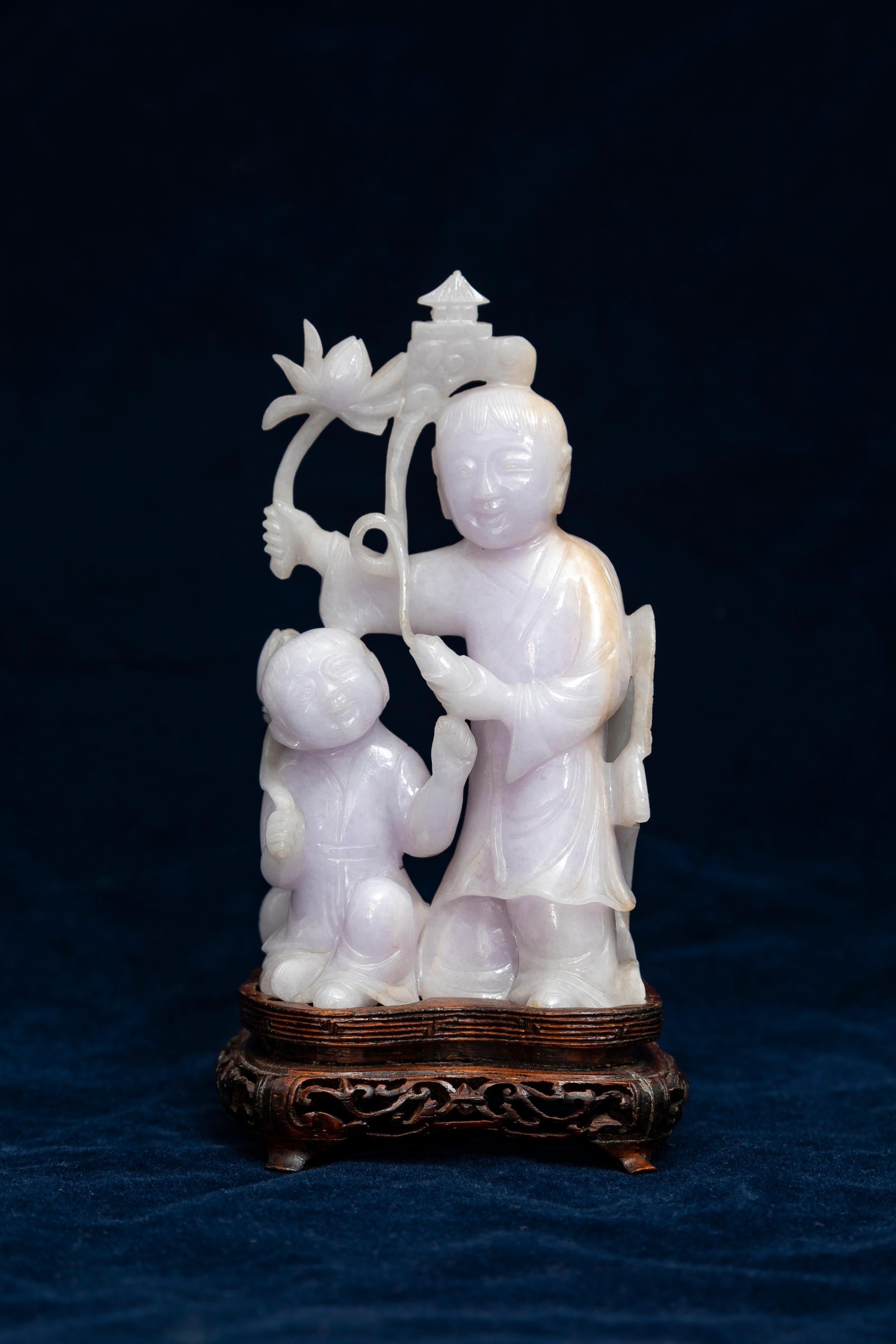 Rare sculpture chinoise en jadéite lavande pâle représentant deux immortels, sur sa base originale en bois sculpté, provenant d'une collection privée.  Un debout et un agenouillé, montés sur un socle en bois ajouré. Le personnage debout tient dans