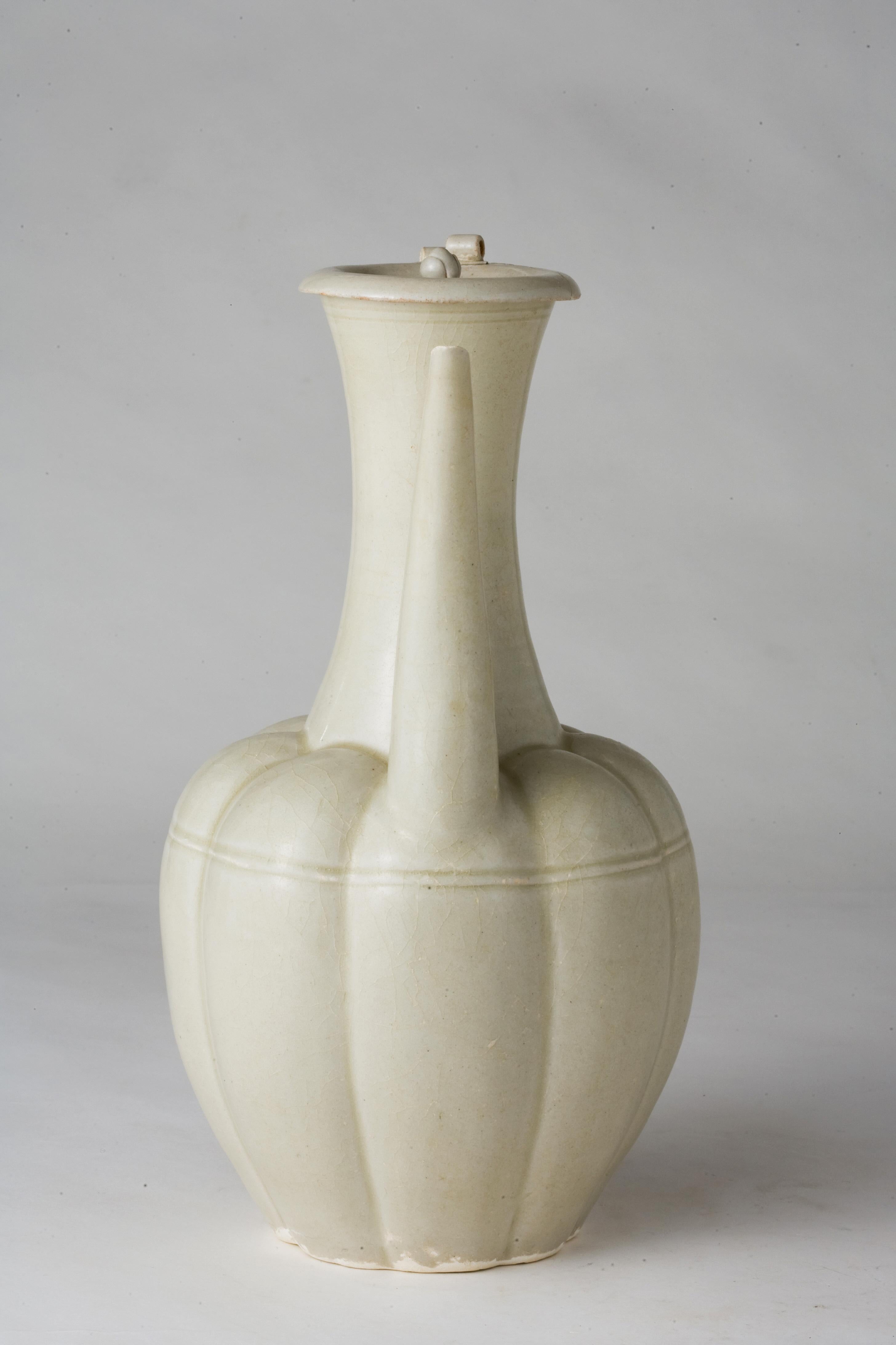 Il corpo ovoidale ottagonale lobato si innalza da un breve piede divaricato a un alto collo a tromba, incastonato sulla spalla con un alto beccuccio ricurvo e sull'altro lato con un alto manico a cinghia, il coperchio bombato sormontato da un finale