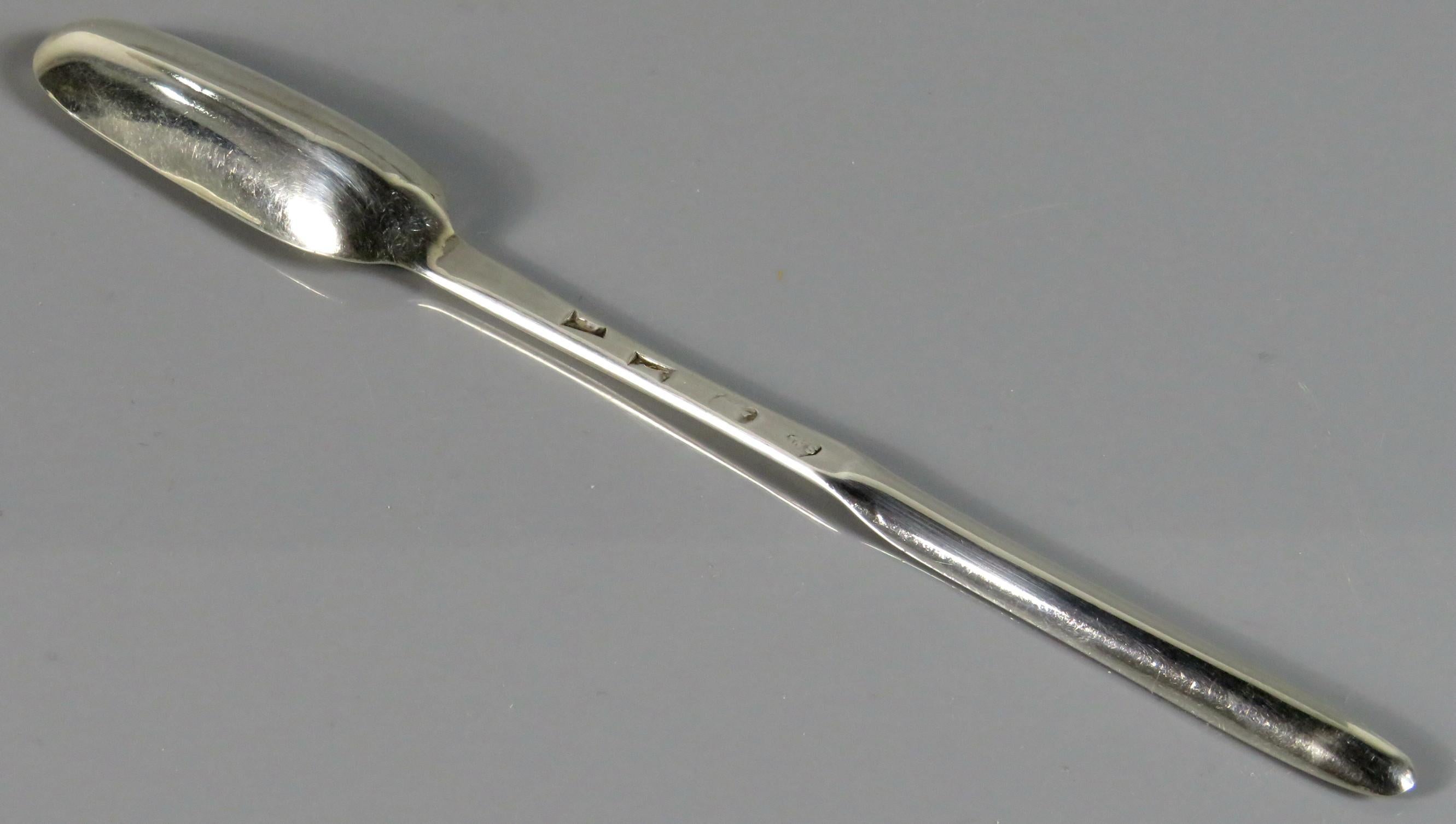 A rare George I sterling silver marrow scoop, showing an elongated bowl at either end of the flattened stem - the heel on the underside of the larger bowl showing a 'rat tail' element. The underside of the stem impressed with London hallmarks, date