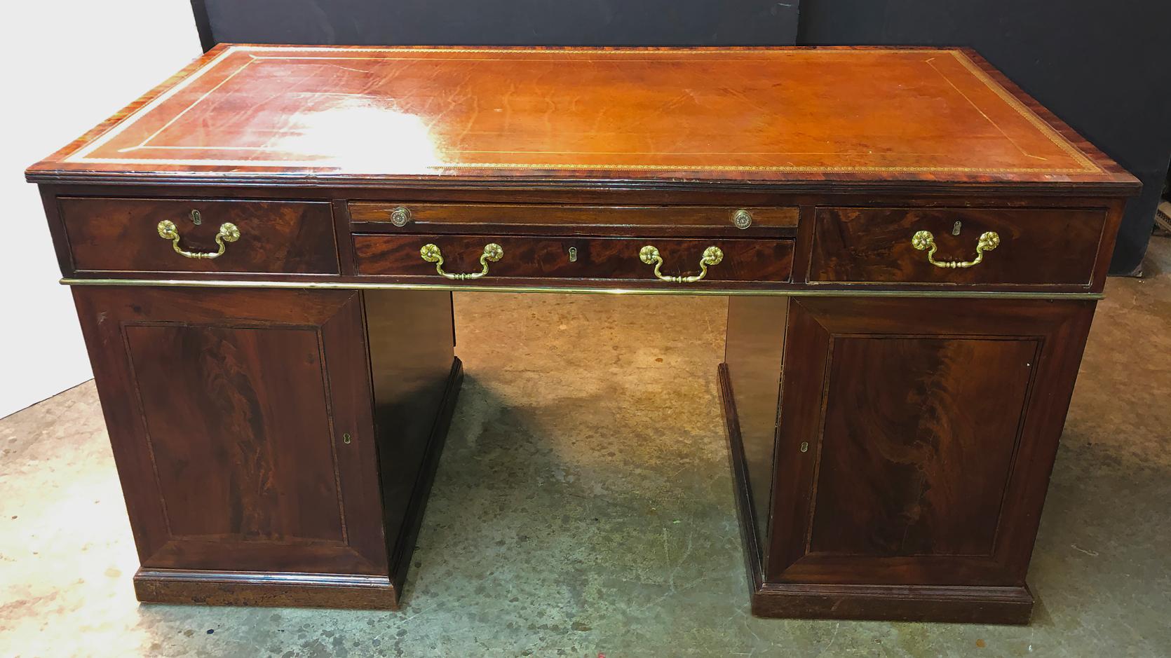 A rare and unusual George III mahogany leather top Partner's desk with two slide-out tooled leather architectural writing slides and raised on cabinet pedestal bases.