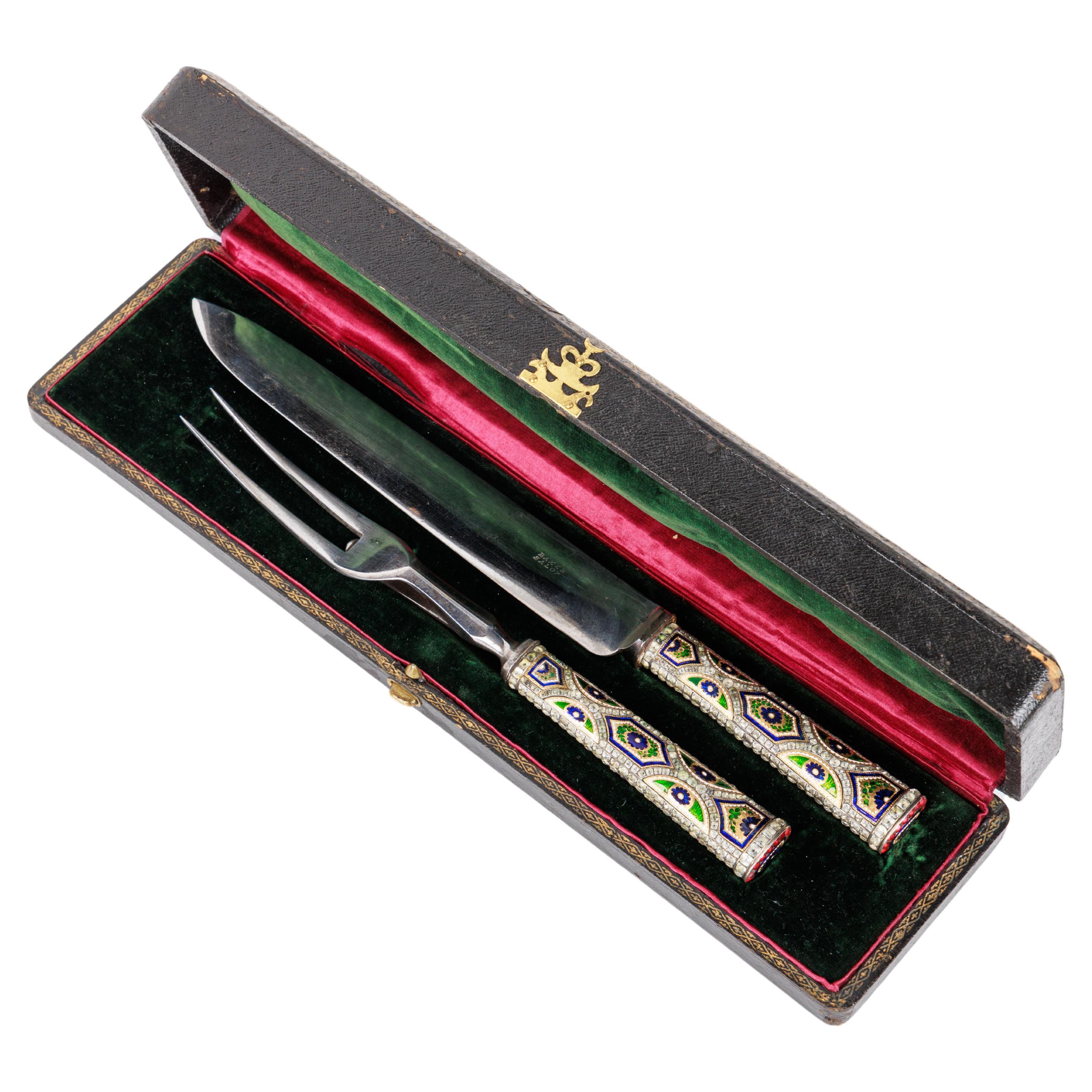 A Rare Gold, Enamel and Jewelled Cutting / Carving Service.

The handles 18th century, Switzerland and the blades 19th century, England.

Comprising a knife and a fork, the handles decorated with blue, green and white gold enamel panels of flowers