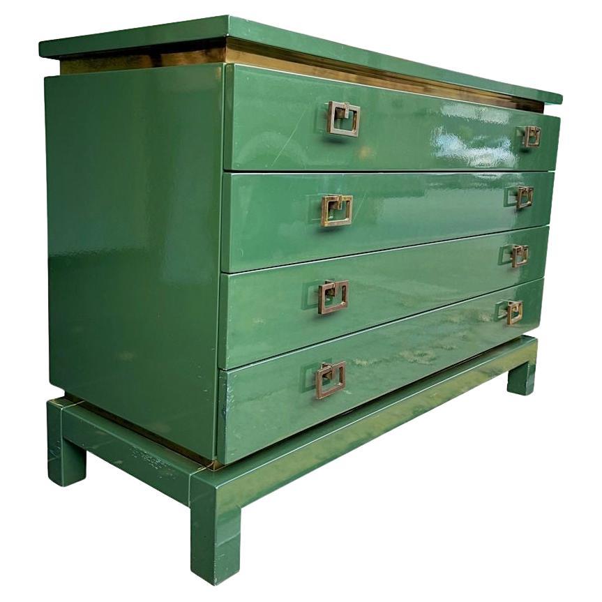 A rare, deep forest green gloss lacquered 1970s four drawer chest of drawers by Guy Lefevre for Maison Jansen with chunky solid brass drop handles and brass inlay detailed surround, In orignal deep green gloss lacquer including the drawer interiors.
