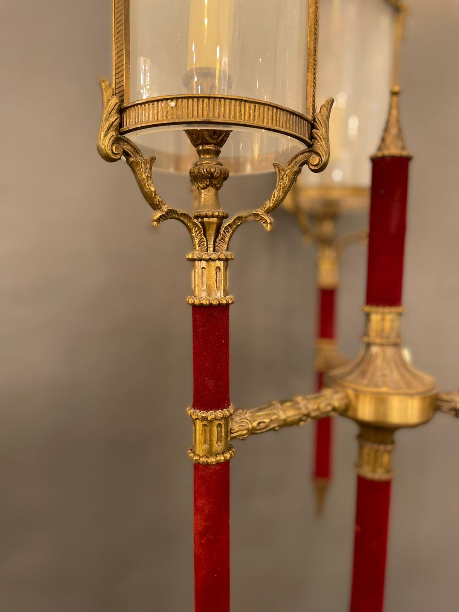 An original floor lamp in bronze adorned with bronze decorations. The arms and the central pole are adorned with fine red velvet with opaline glass shades. The floor lamp has a solid base in bronze with decorations. Italy 1930s
