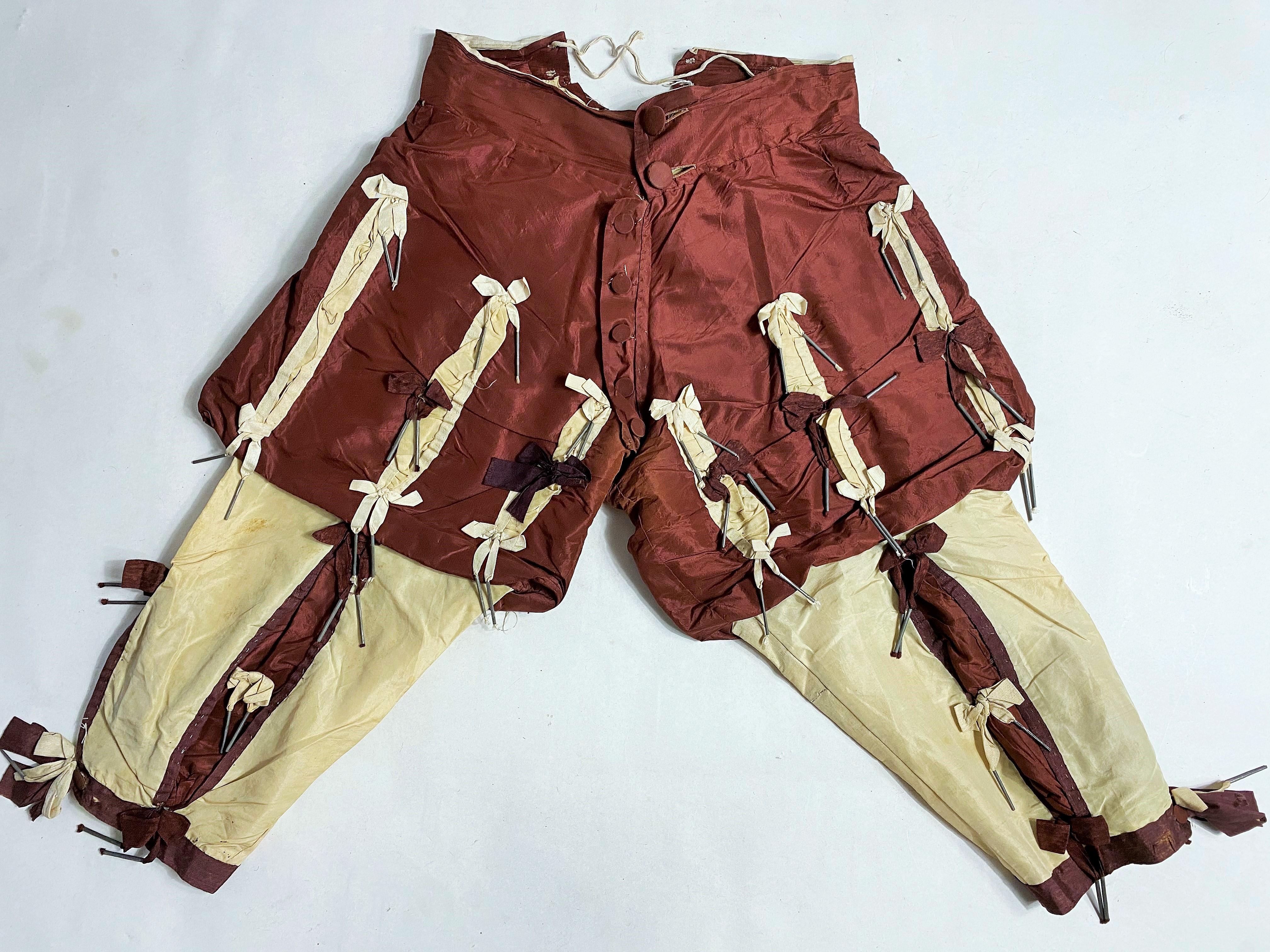 Circa 1780
England

Exceptional British sportswear, probably Jockey, in cream and aubergine silk taffeta dating from the last quarter of the 18th century. Slim-fitting athletic blouse, high buttoned collar in front, aubergine ribbon appliqué