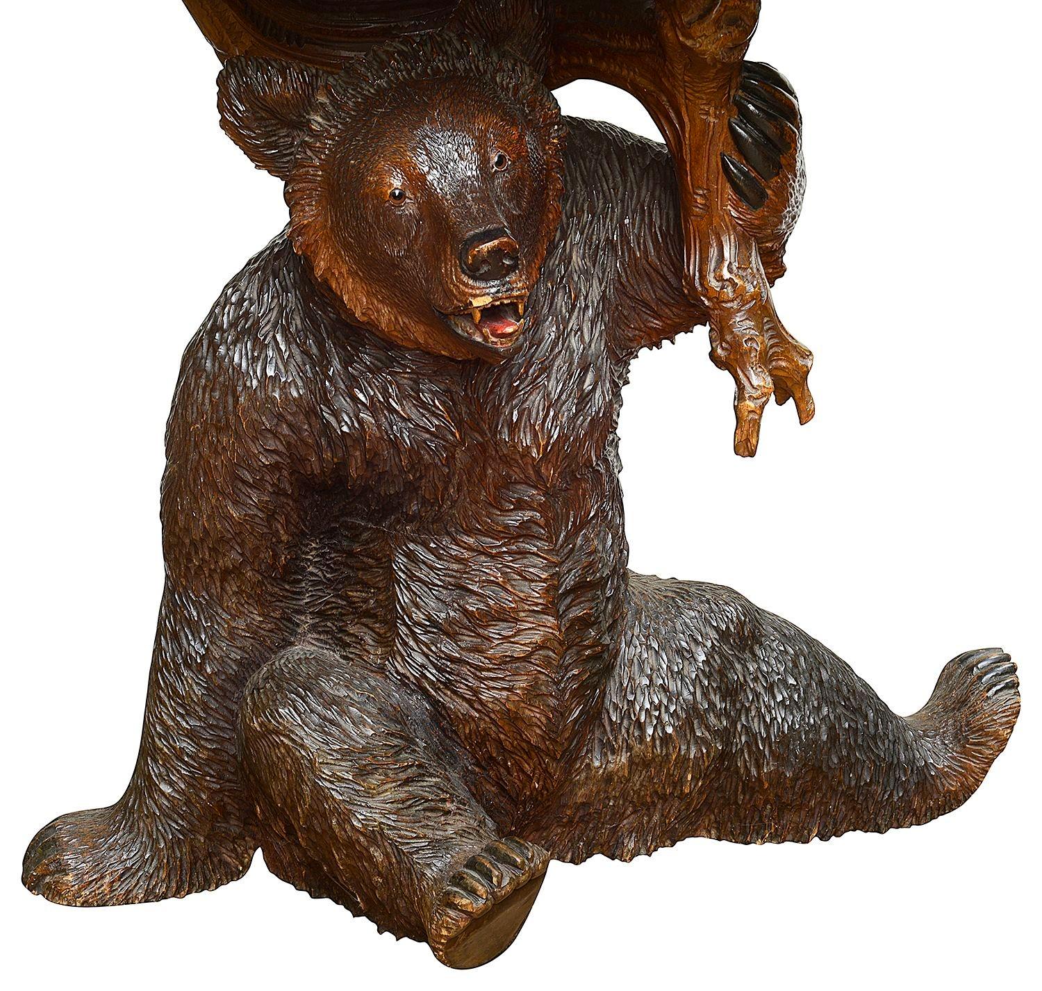 A rare and impressive 19th century Swiss Black Forest carved Lindenwood Bear sitting down supporting the table top, this having carved scrolling foliate decoration.
 
Batch 72/73.