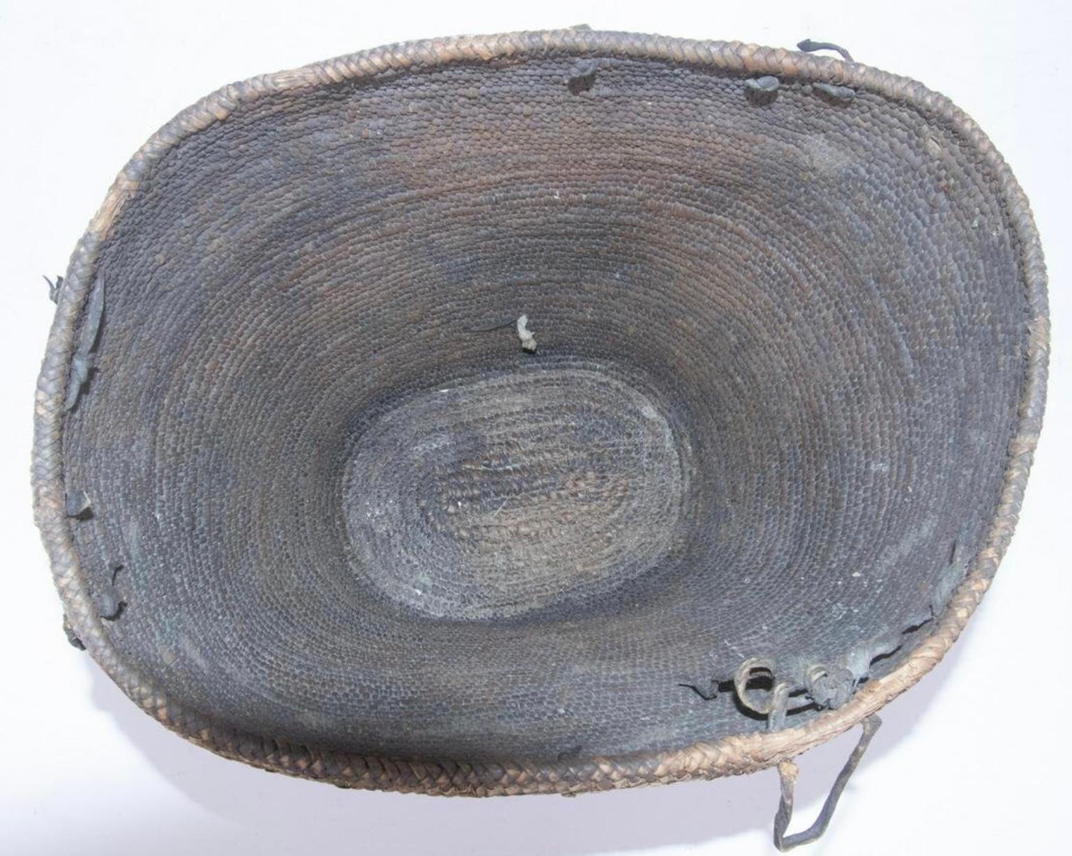 Rare large early Northwest Coast Salish hard burden basket dating from the mid to late 1800's. The basket is finely woven from split cedar bark and root that form a wave pattern that encircles the periphery. Note the old deer hide strap carrying