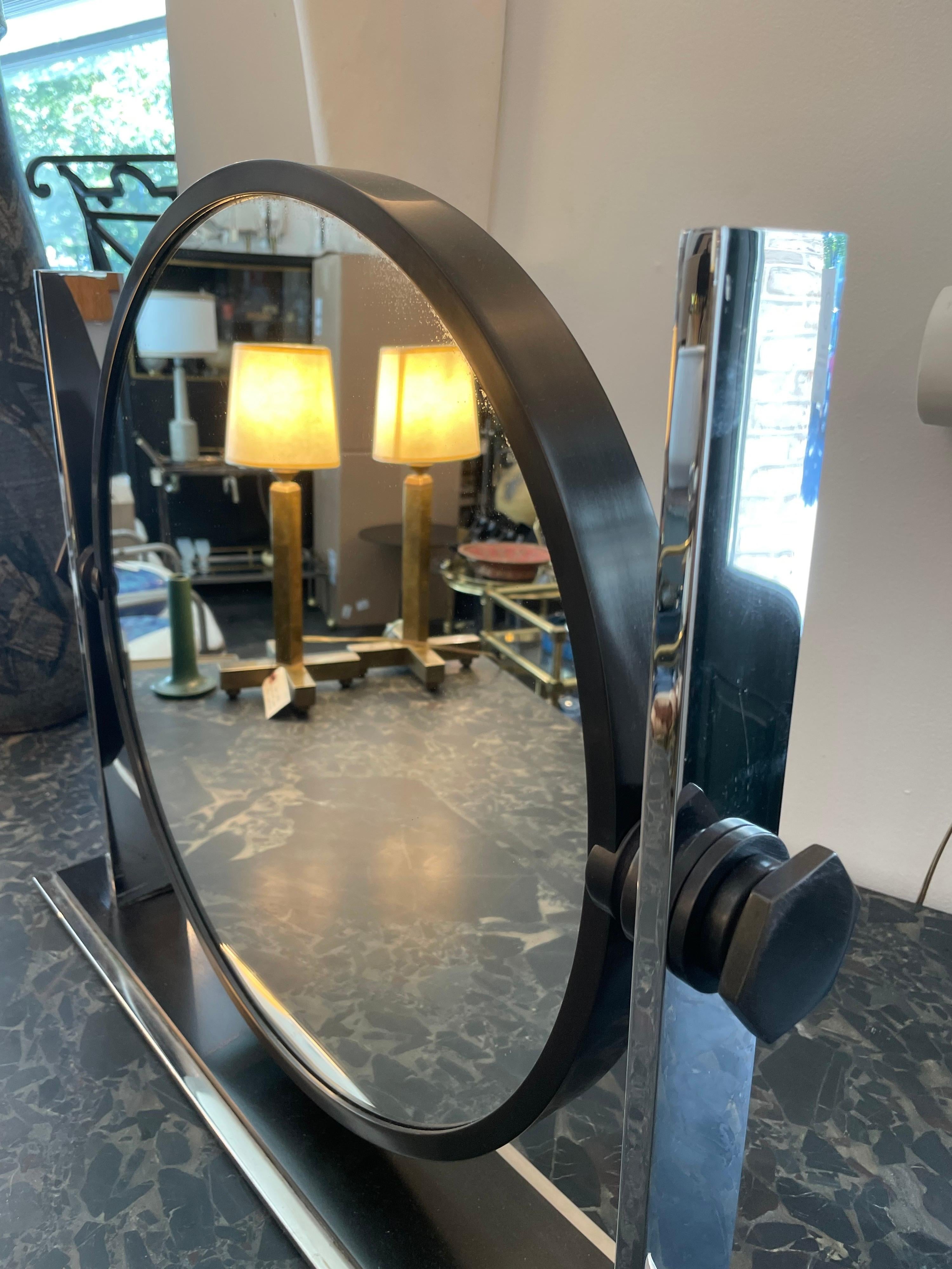 Ce grand miroir de maquillage iconique Karl Springer, d'inspiration Art déco, date des années 1970-1980. Fabriqué en acier inoxydable et en laiton bronzé, il comporte des miroirs sur les DEUX côtés et des boutons d'accentuation à écrou hexagonal.