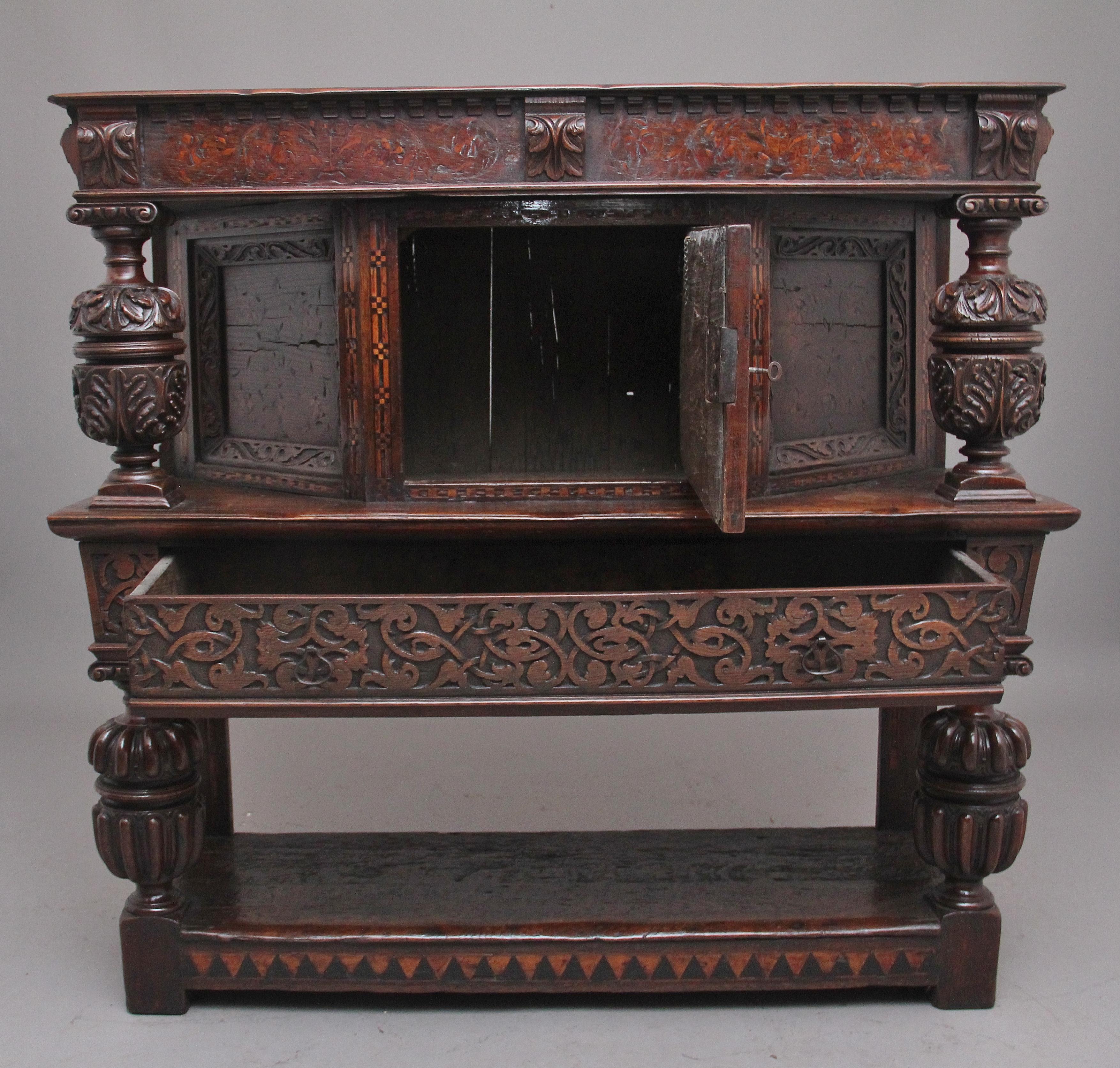 A very rare late 16th century oak court cupboard dating from the Tudor period, having a wonderfully rich oak patina, beautifully carved supports and rails, with holly and bog oak inlay, the top section having a central cupboard with angled panels