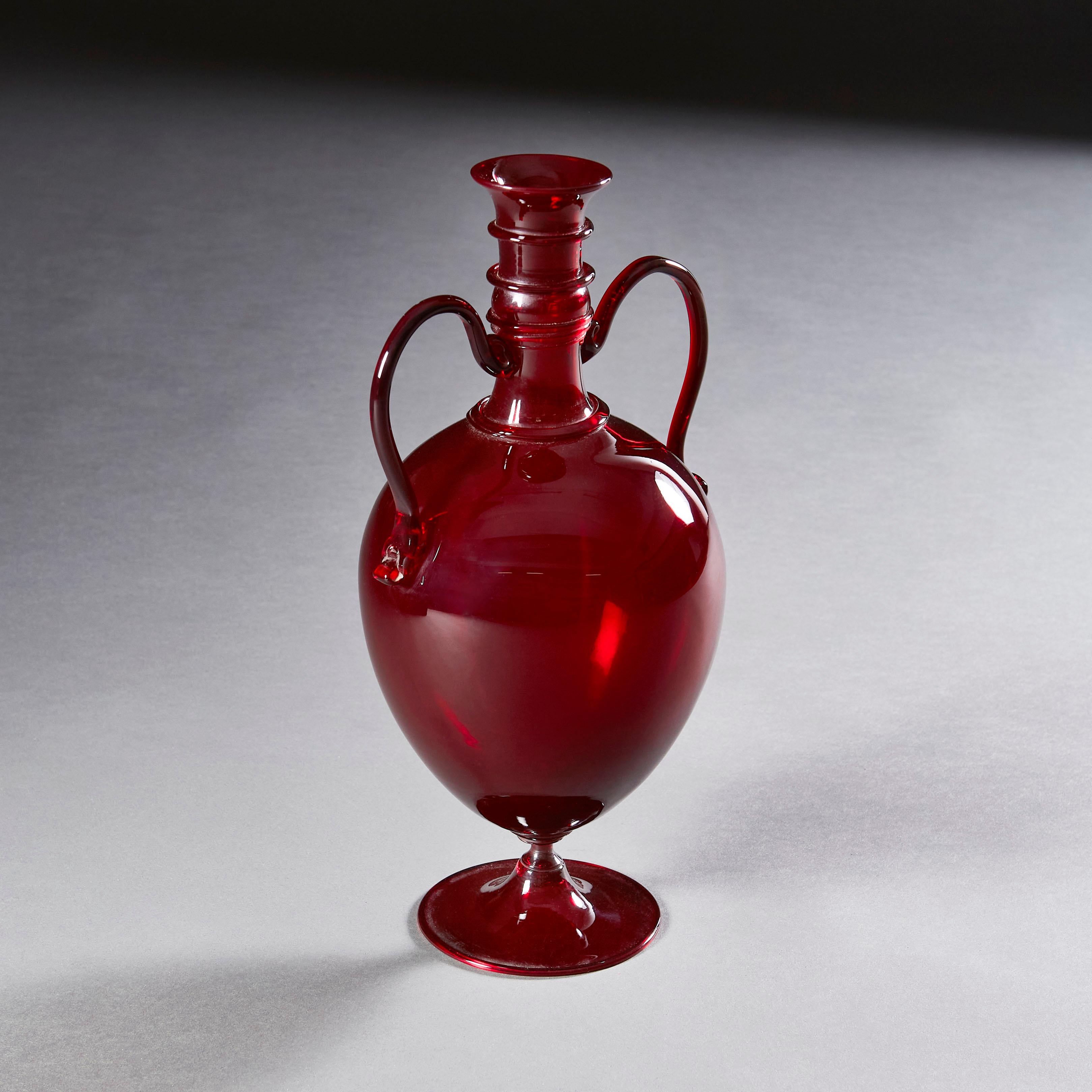 A rare mid nineteenth century red glass vase of amphora form, with handles attaching to the body of the vessel in delicate scrolls, all supported by a very fine tip, that seems to give the illusion of the body of the vessel floating above the base.