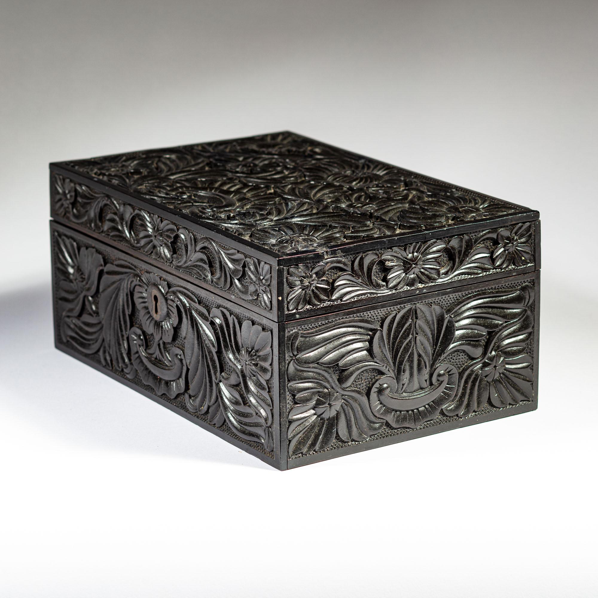 A rare mid 19th century carved ebony workbox, profusely carved with foliage and floral details on all sides, the lid opening to an inlaid bone elephant fitted interior with a removable tray. Retaining the original lock.

Ceylon, circa