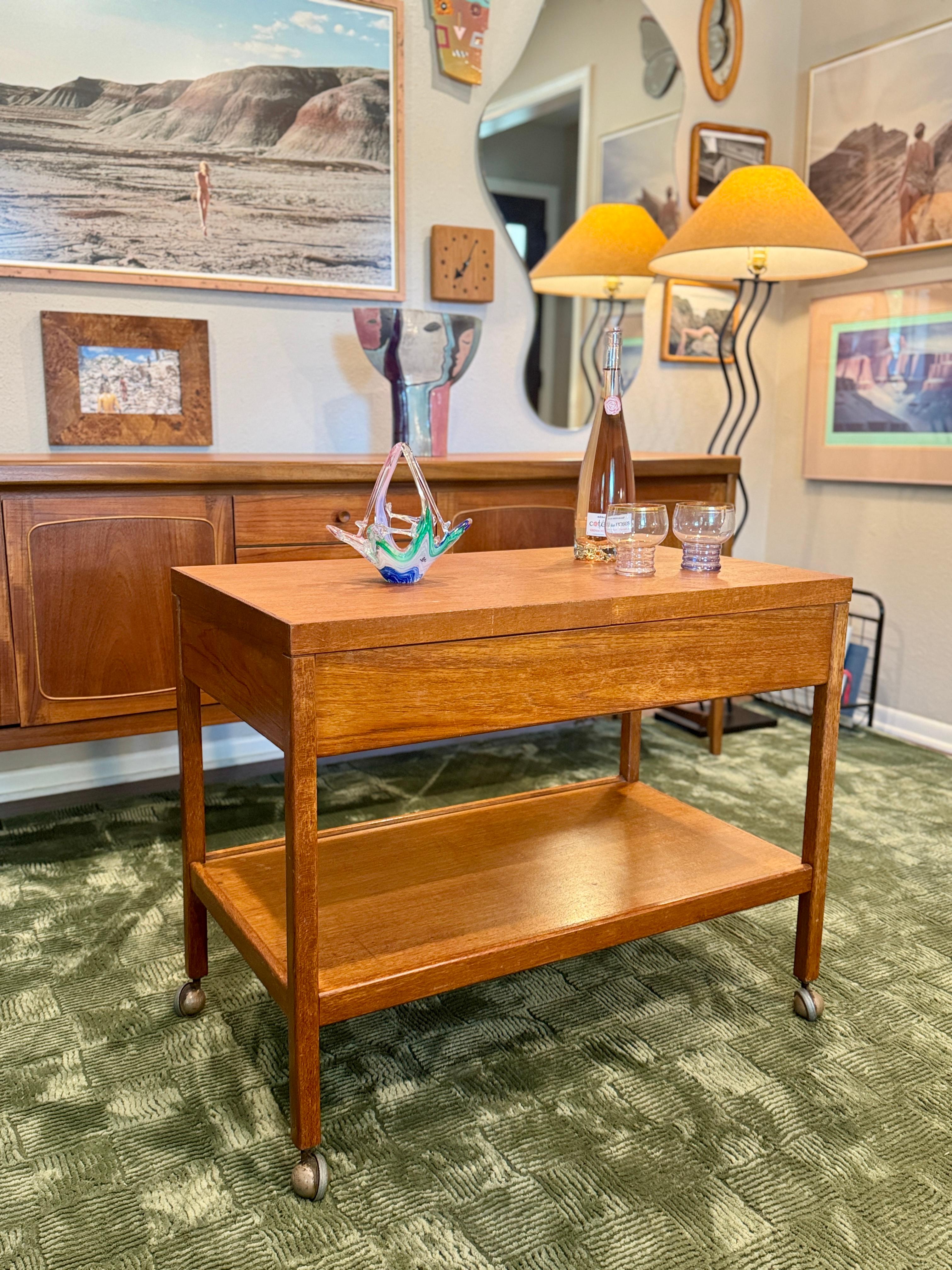 A rare mid century modern 2 tier bar or serving cart, influenced by the clean, functional lines of Hans Jørgen Wegner and possibly manufactured by Remploy, though unmarked. Circa 1960s/70s. This unique piece features a clever sliding top mechanism