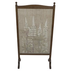 A rare oak and floral embroidery fire screen with stylized foxgloves