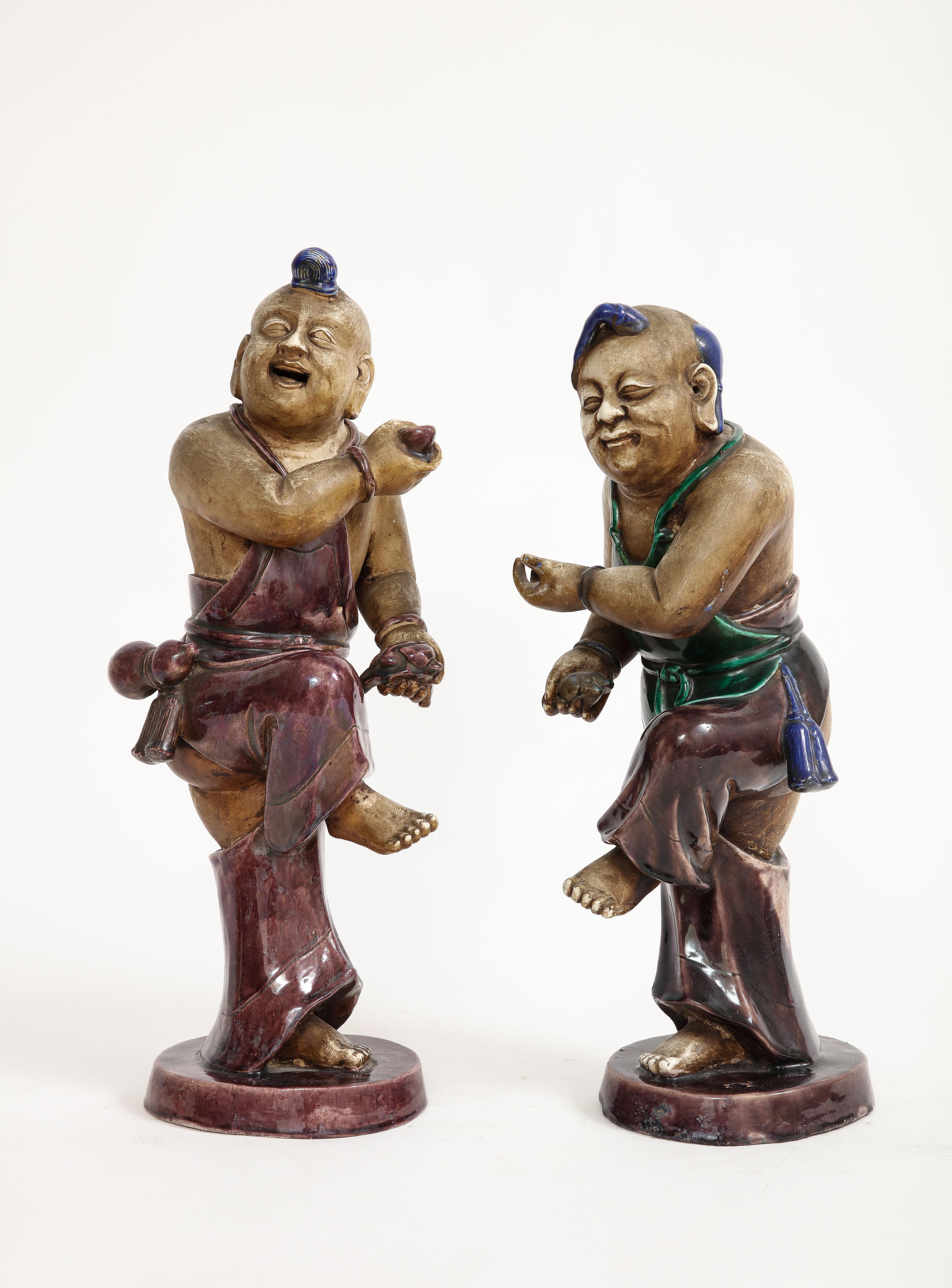 A Rare Pair of Chinese Kangxi 18th Century (1710) Biscuit Porcelain Figures of Boy with Enamel Decoration.  These captivating figures, seemingly caught in the midst of a joyous dance, beckon visitors to immerse themselves in the rich heritage and