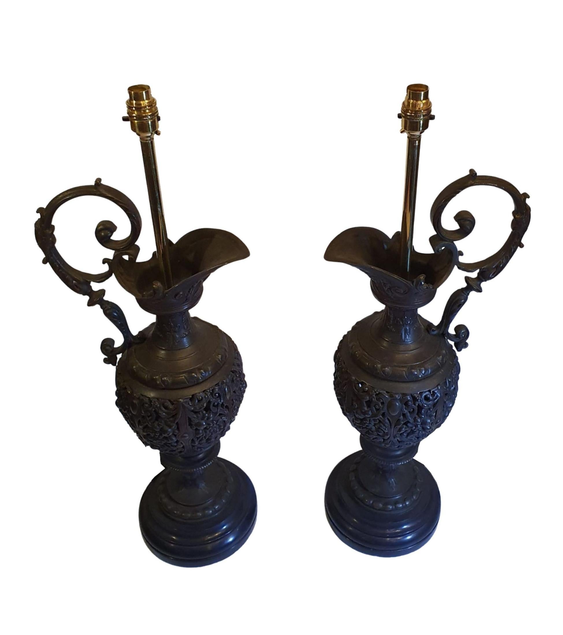 Une paire très rare d'aiguières en bronze du XIXe siècle transformées en lampes de table. Le corps en relief magnifiquement moulé représente des détails élaborés de motifs de volutes et de feuillages avec d'élégantes poignées à volutes soutenues par