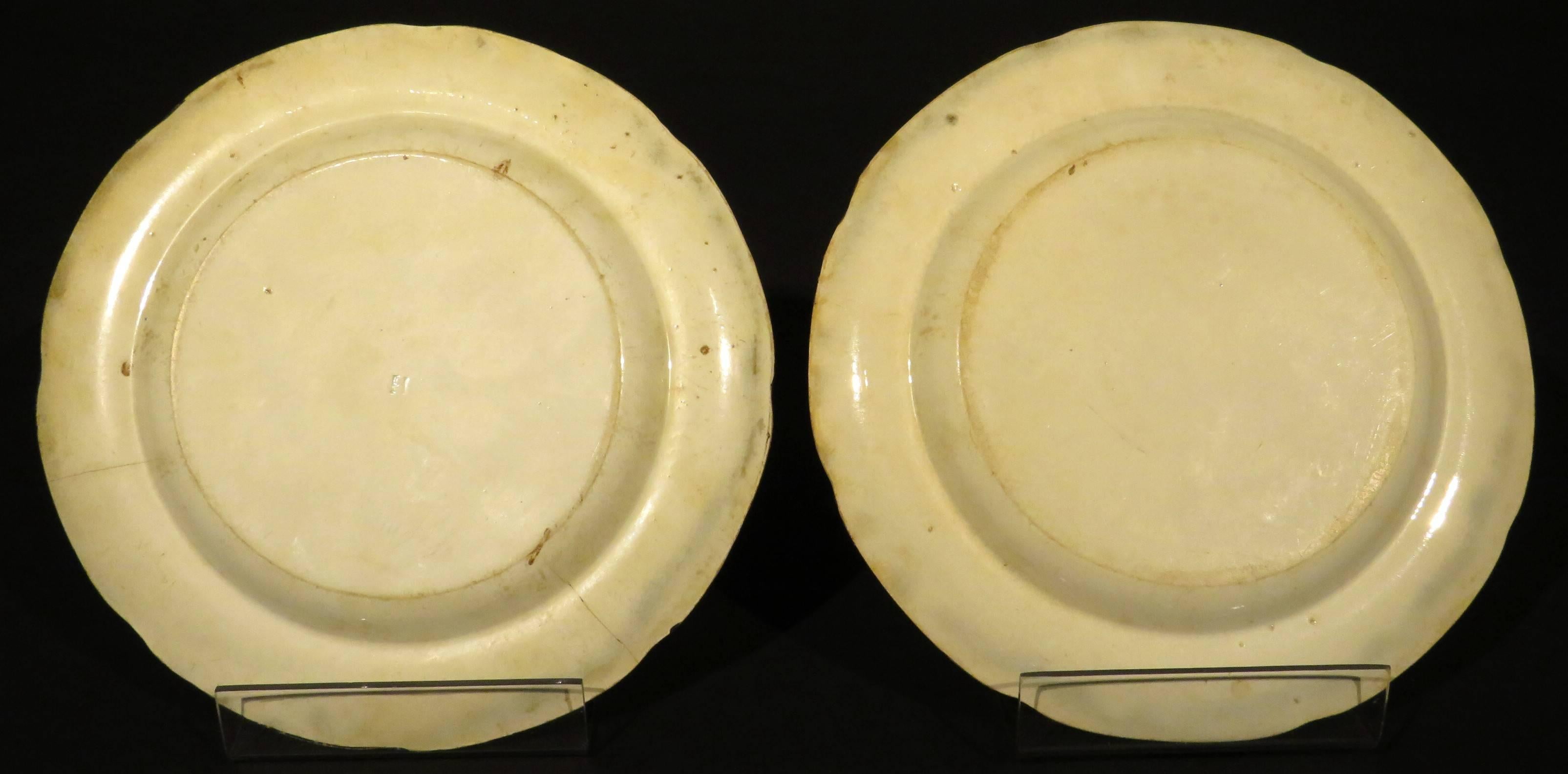 A rare pair of early 19th century Herculaneum pottery cabinet plates decorated in the 'Greek Pattern'. Both plates showing black and white transfer decoration depicting classical themes, set against a terracotta vermiculé ground, the underside