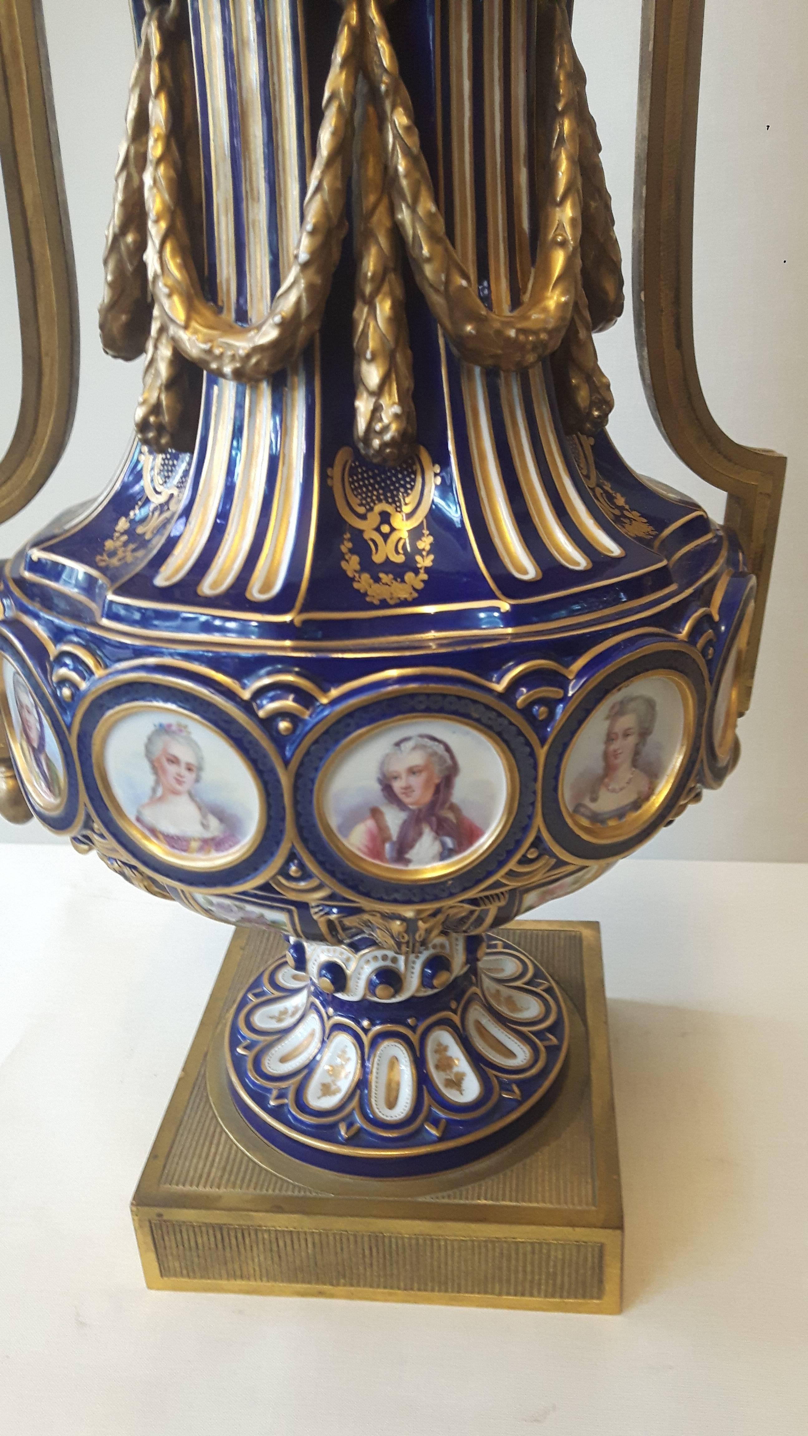 Une importante paire de vases de style Louis XIV Sèvres, décorés à la main avec des cartouches du roi, de sa famille et de ses maîtresses. Les couvercles sont moulés en couronne ; des guirlandes en porcelaine moulées à la main embellissent le corps,